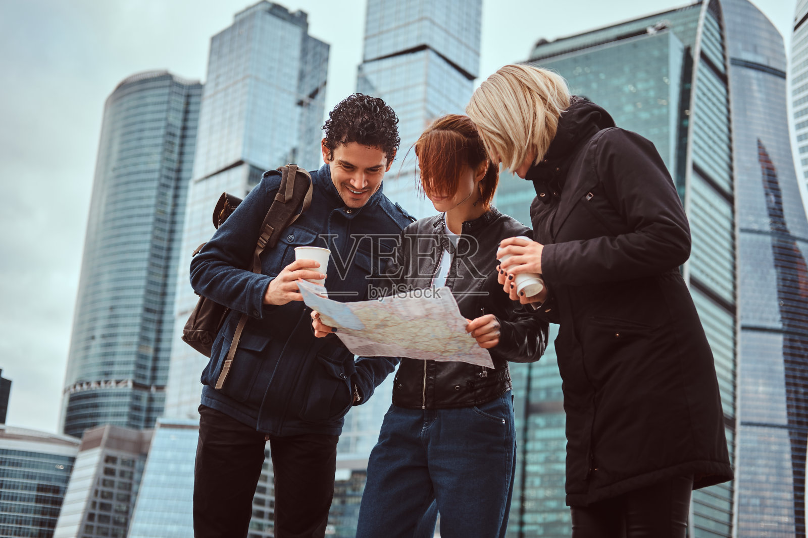 一群游客在摩天大楼前搜索地图上的位置照片摄影图片