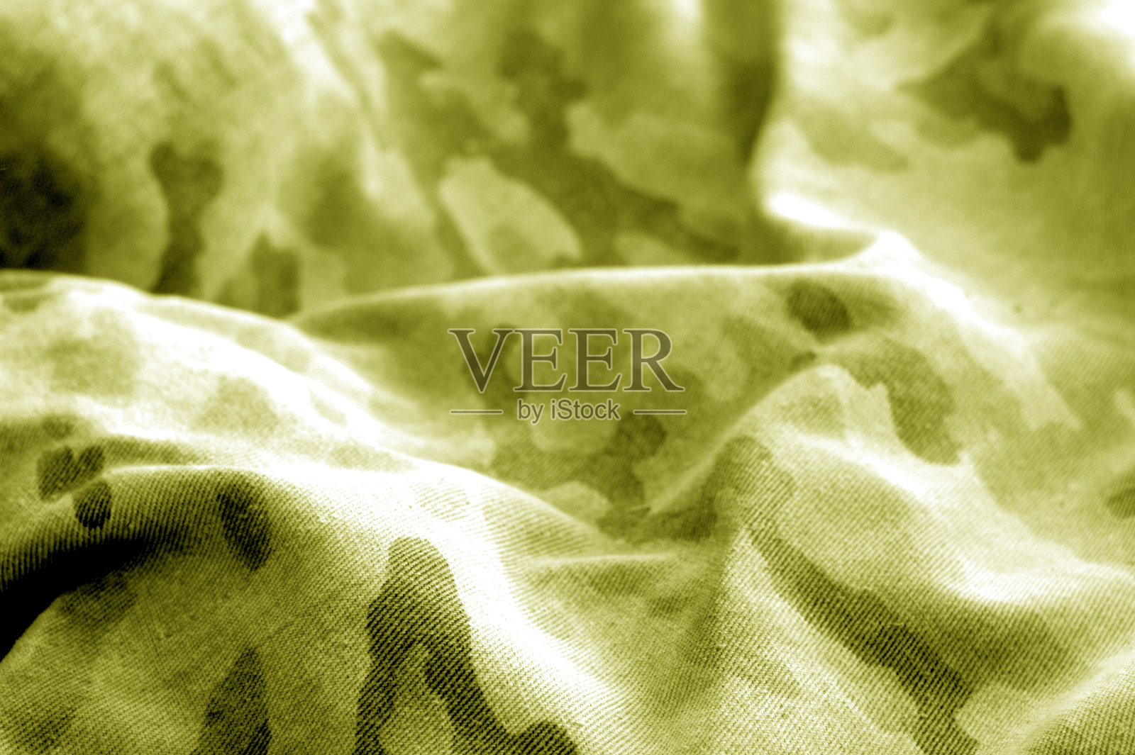 旧的迷彩布料，黄色调的模糊效果。照片摄影图片