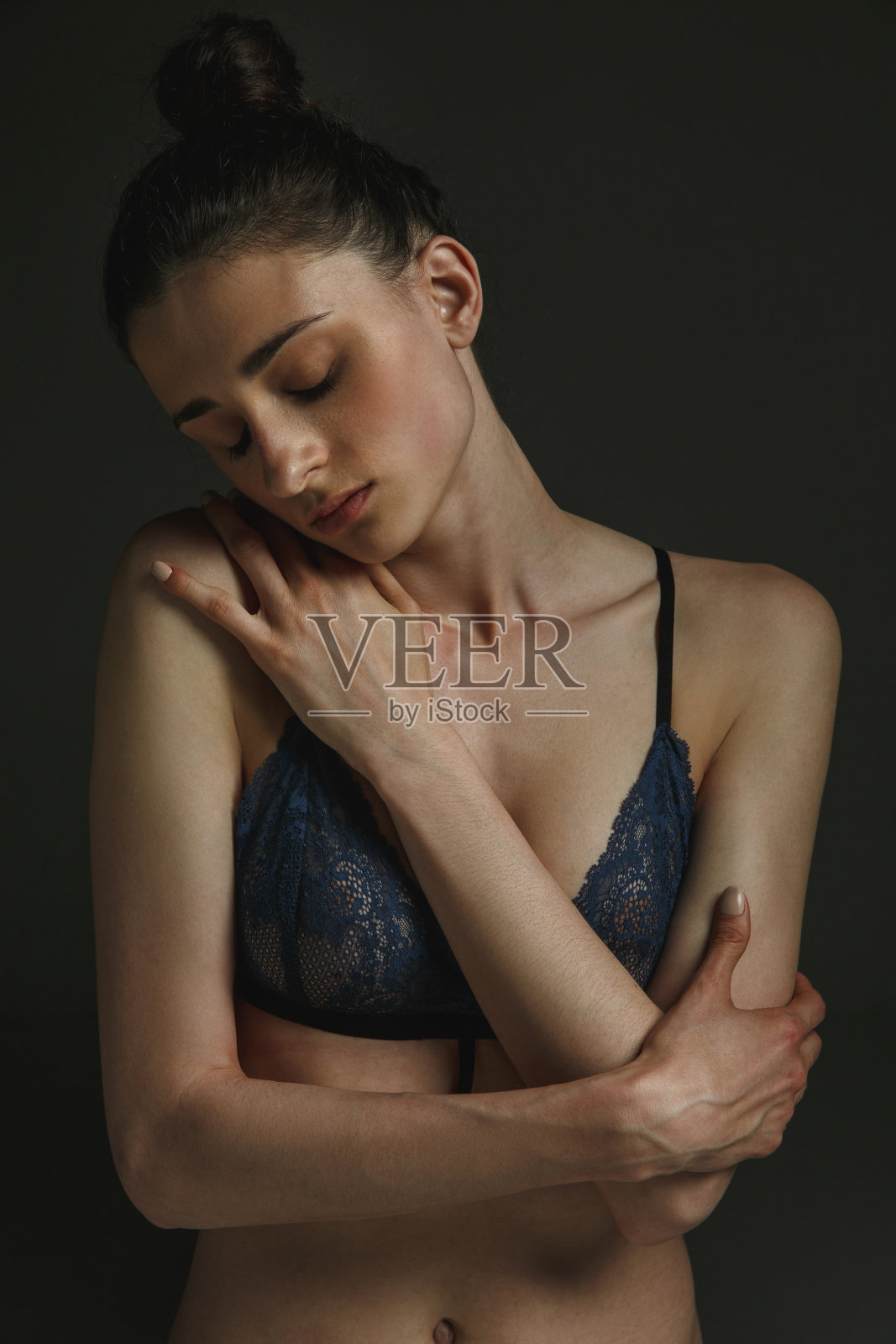 在黑暗演播室背景下的年轻悲伤女人的半身像照片摄影图片