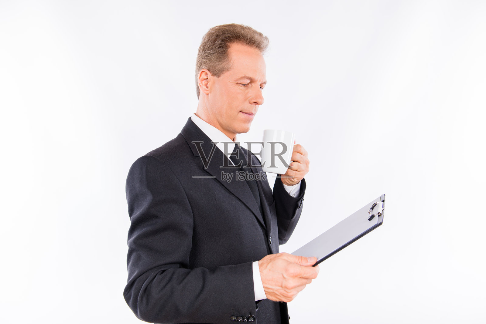 一个有魅力的成熟商人手里拿着文件夹和马克杯照片摄影图片