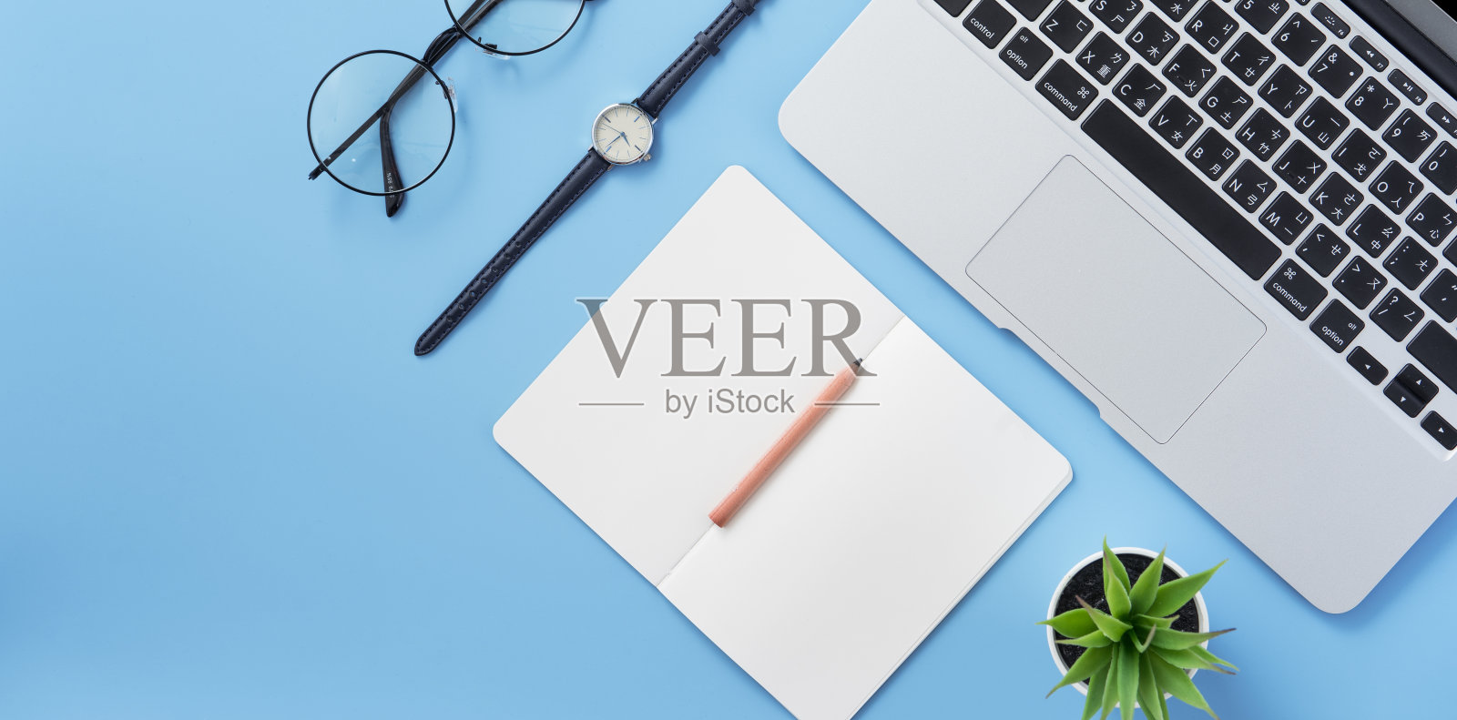 女孩在一个最小的干净的浅蓝色桌子上写白纸或会计，上面有笔记本电脑和附件，复印空间，平躺，俯视图，模型照片摄影图片