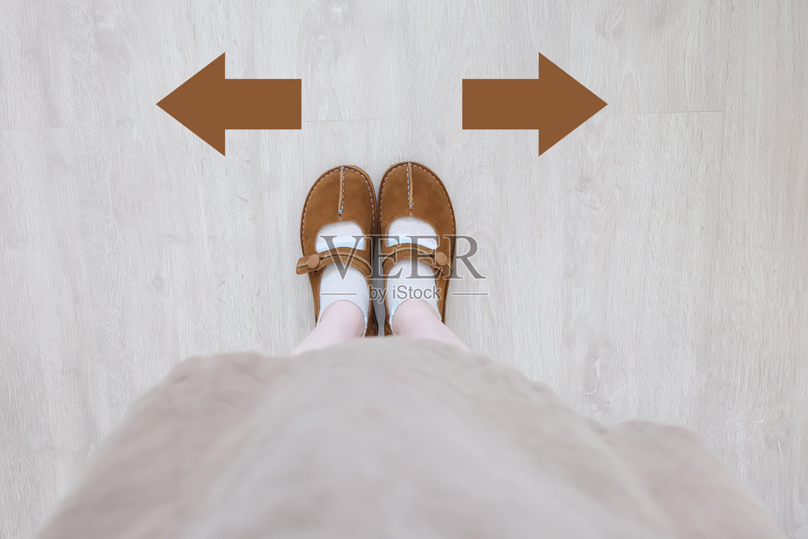 顶视图的棕色靴与不同的棕色决定箭头。一双站立的脚。鞋步行方向上的木地板背景。照片摄影图片