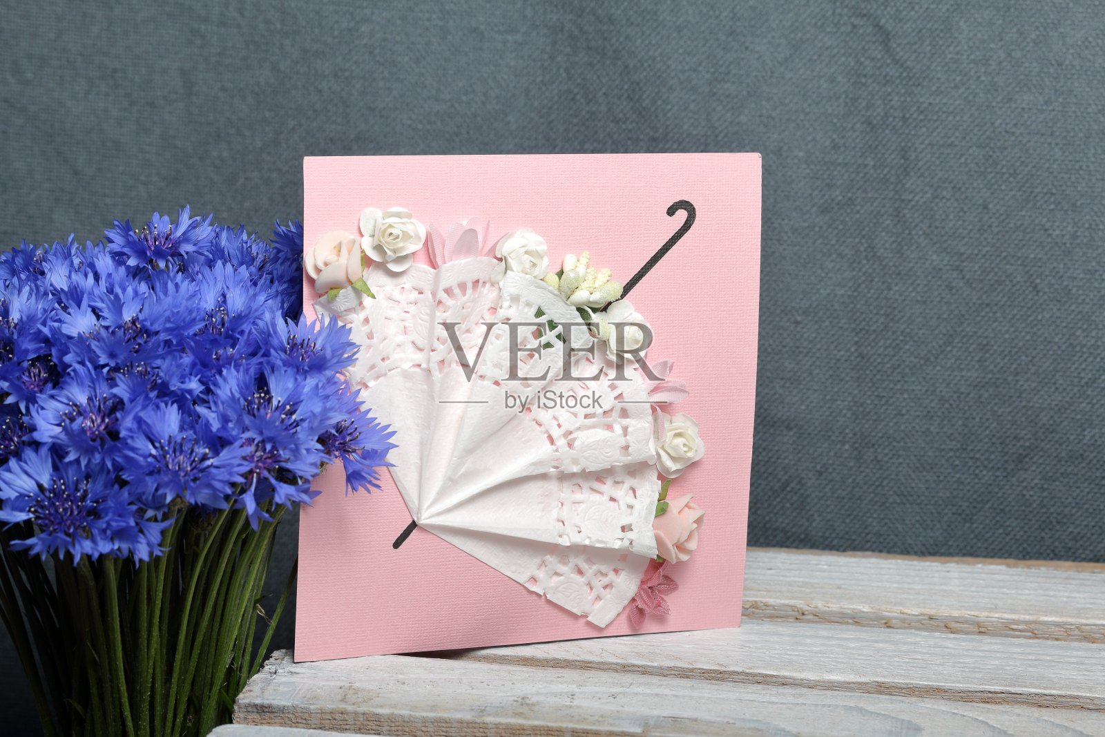 一束矢车菊和一张贺卡。在一个灰色的背景。矢车菊或蓝色的矢车菊(矢车菊属)，有蜘蛛般柔软的线状披针形叶子和蓝色的花。照片摄影图片