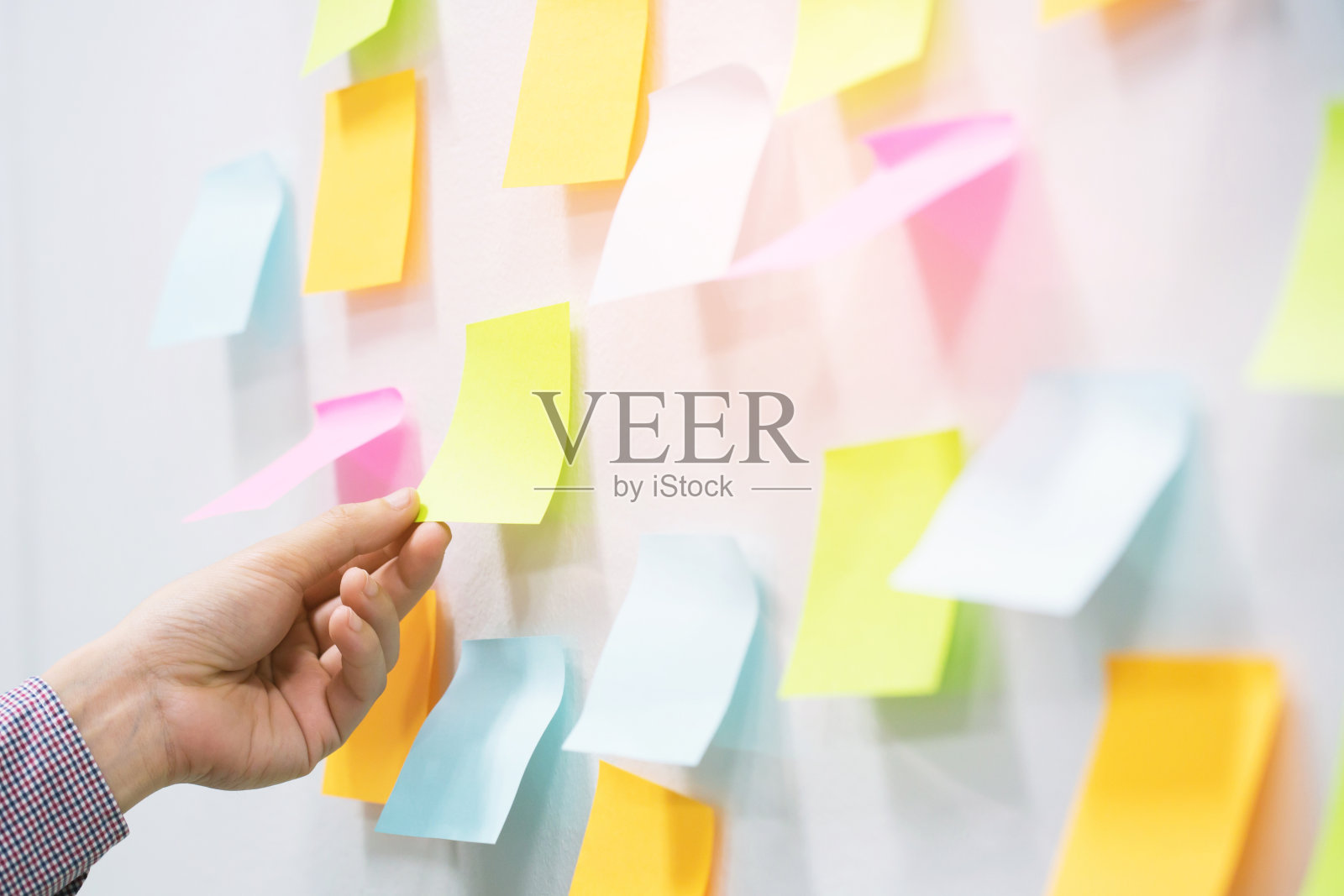 在会议室的墙上，近手的人、商人、记事本。贴，贴，便条纸，提醒，日程表，公告板。五彩缤纷的复制空白。软的焦点。照片摄影图片