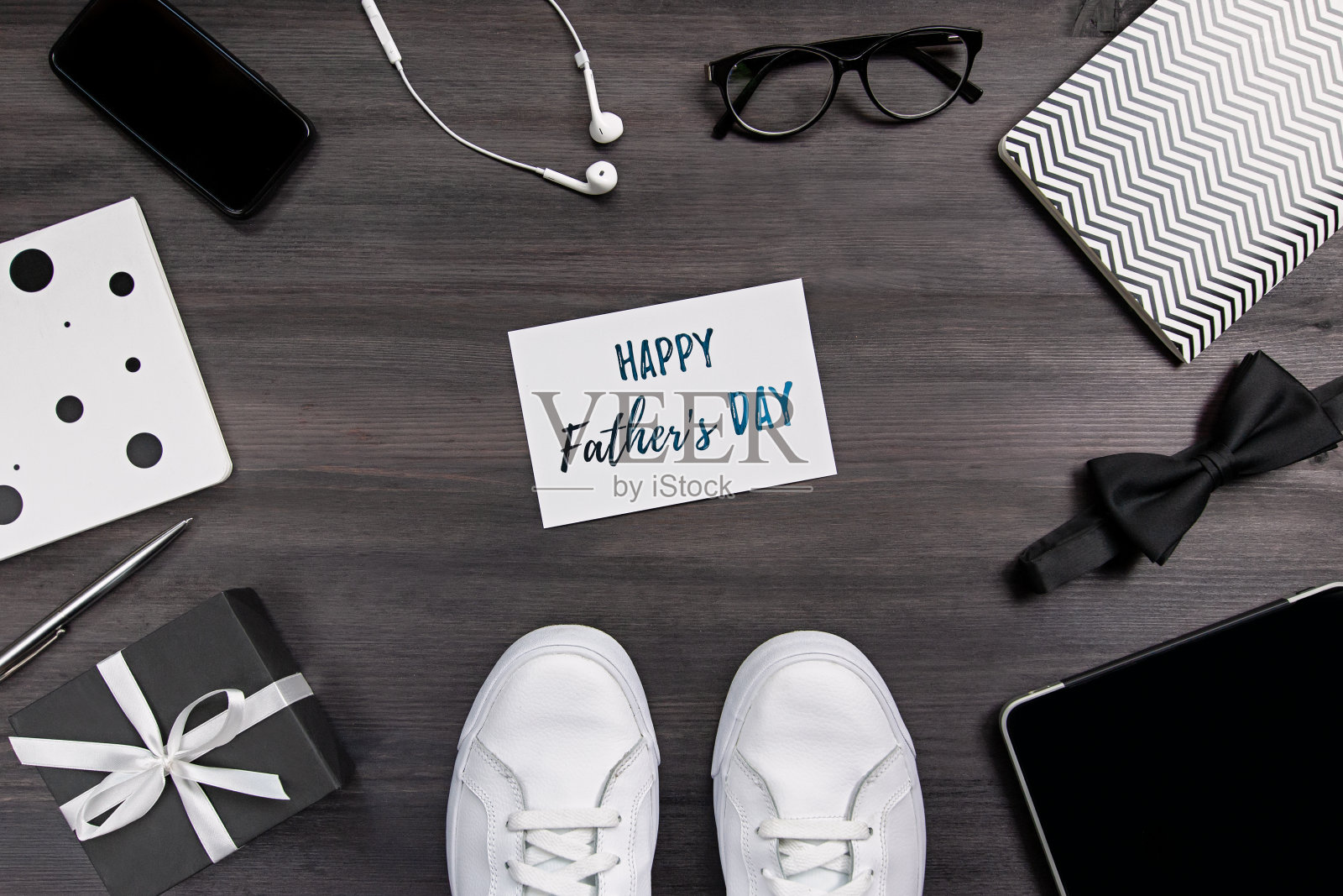父亲节贺卡与男性配件，白色休闲运动鞋，小玩意在深色木制背景照片摄影图片