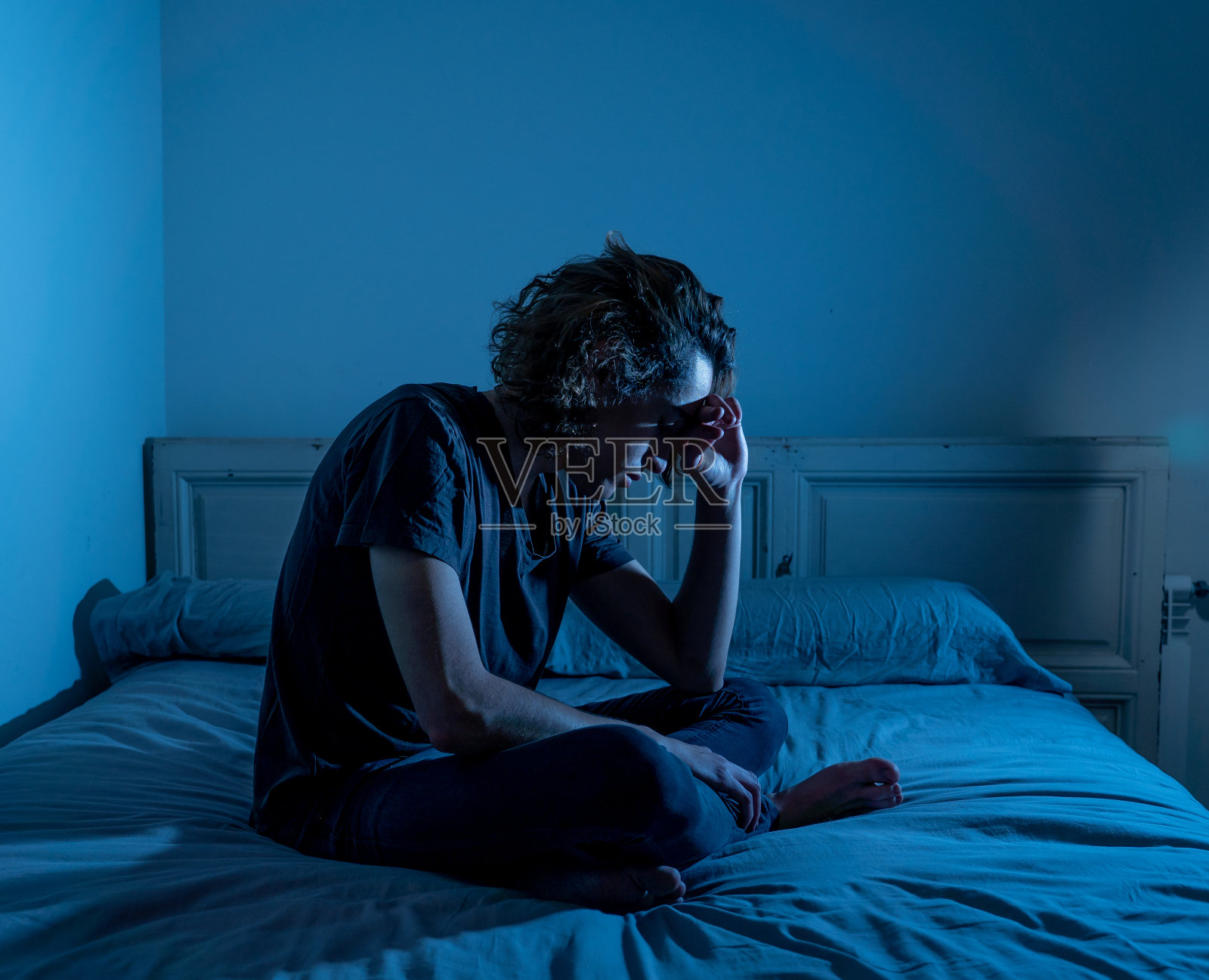 沮丧的千禧一代男性哭泣，感到悲伤、受伤和绝望，遭受抑郁症折磨。沮丧的青少年遭受欺凌或虐待，独自一人绝望地坐在床上。青少年心理健康。照片摄影图片