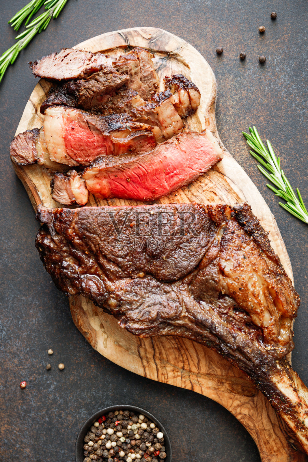 烤干陈年大理石牛排的俯视图，黑木板上的战斧与香料。平躺，晚餐的概念。照片摄影图片