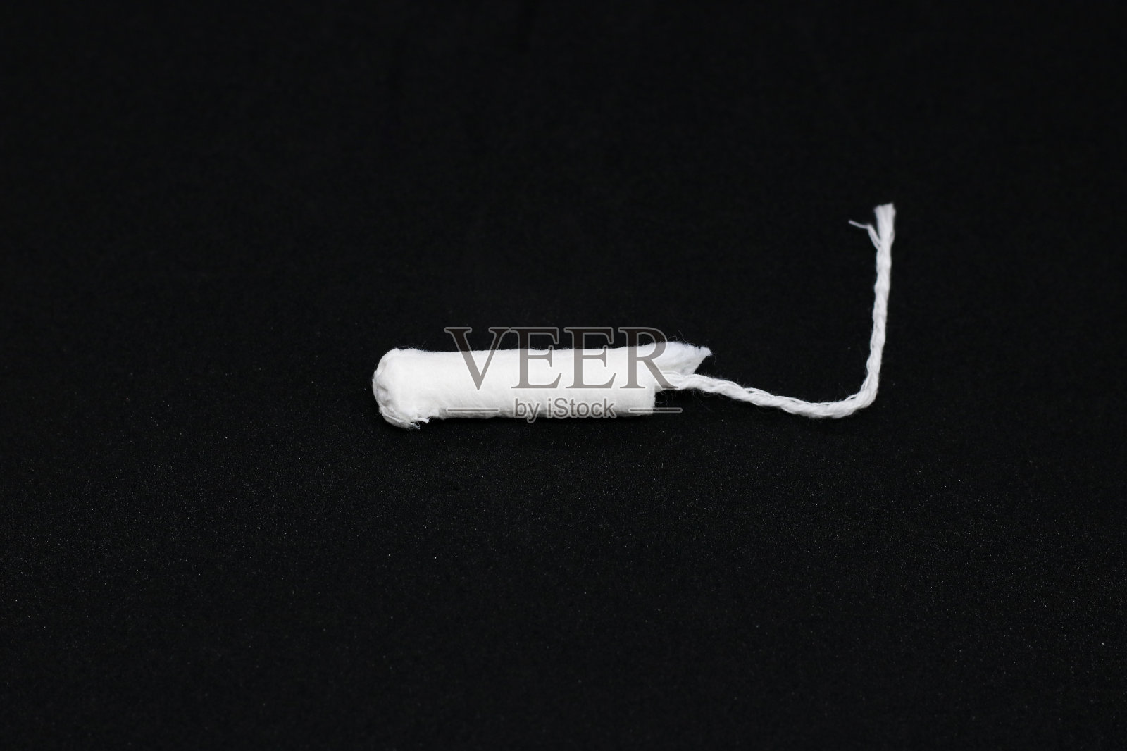 女性卫生产品。卫生棉条和垫圈靠近黑色背景。一个女人的手。文本。照片摄影图片