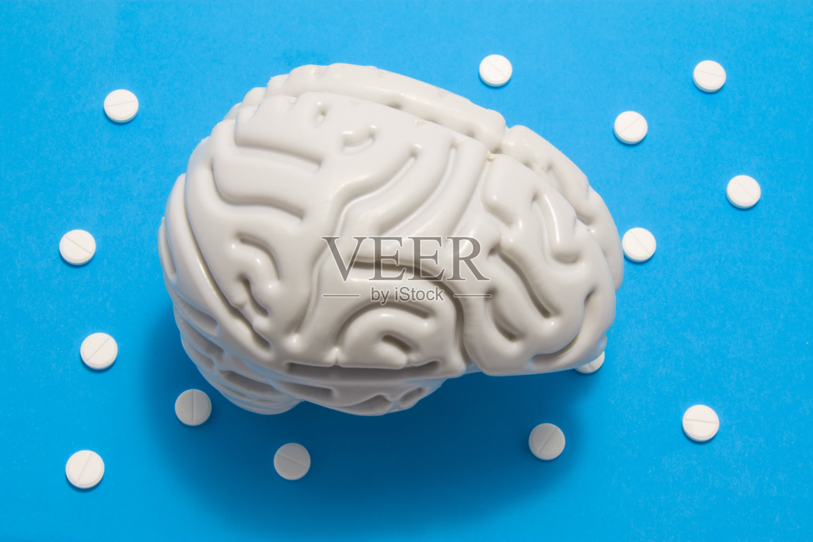 3D大脑解剖模型在蓝色的背景下，周围点缀着白色的圆点丸子。医学概念是通过药理学的片剂、药物疗法、化疗治疗脑部疾病照片摄影图片
