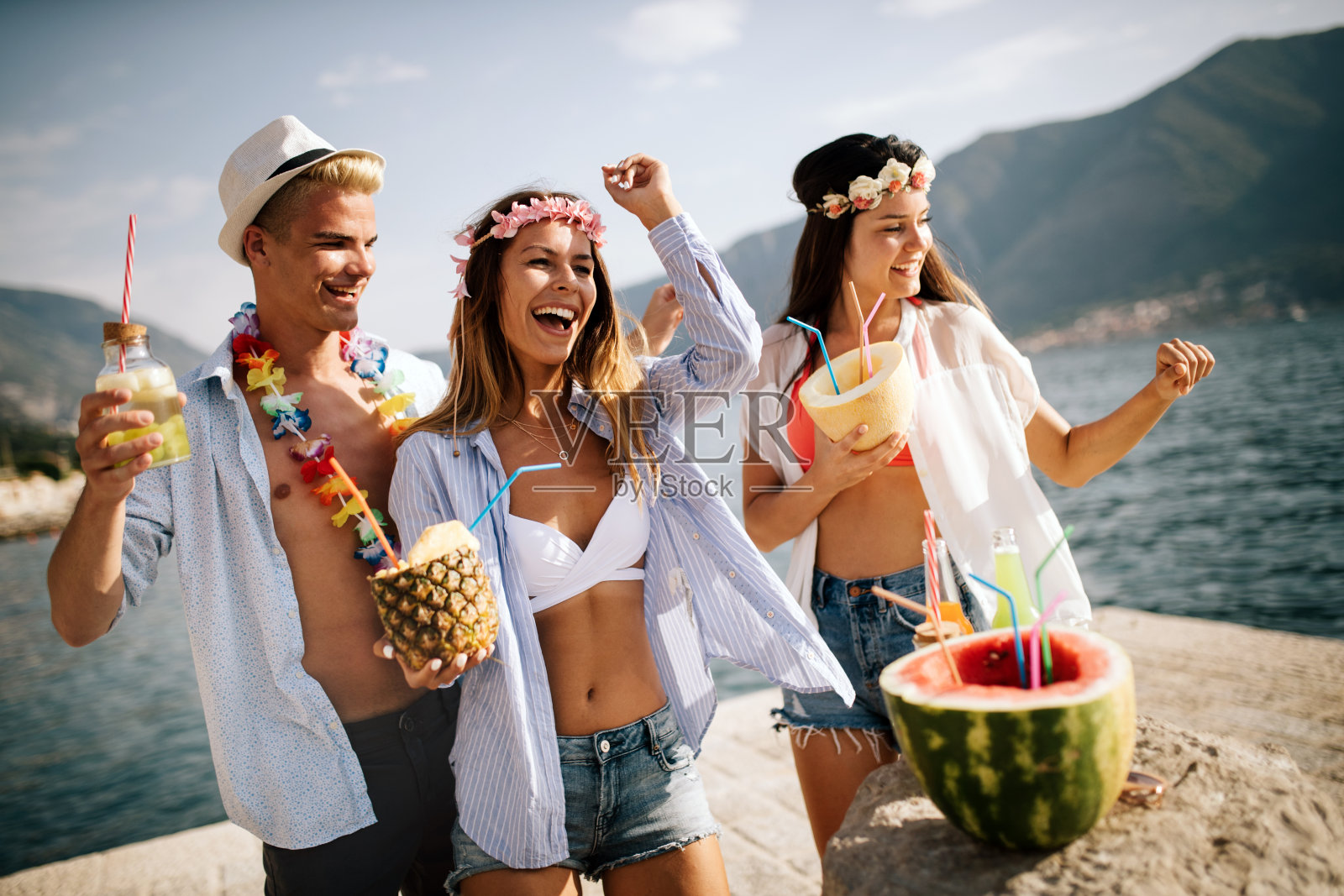 朋友们一起在海滩上玩，喝着鸡尾酒照片摄影图片