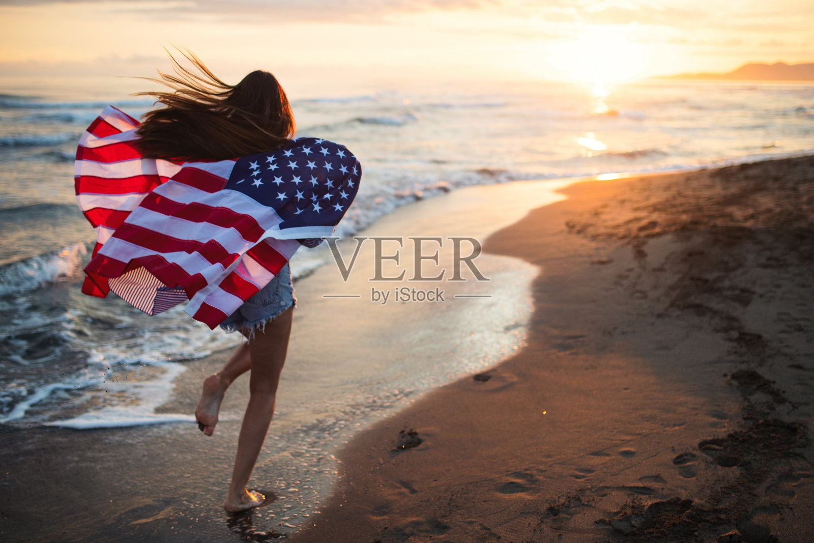 快乐的女人在海滩上跑步，庆祝独立日，享受美国的自由照片摄影图片