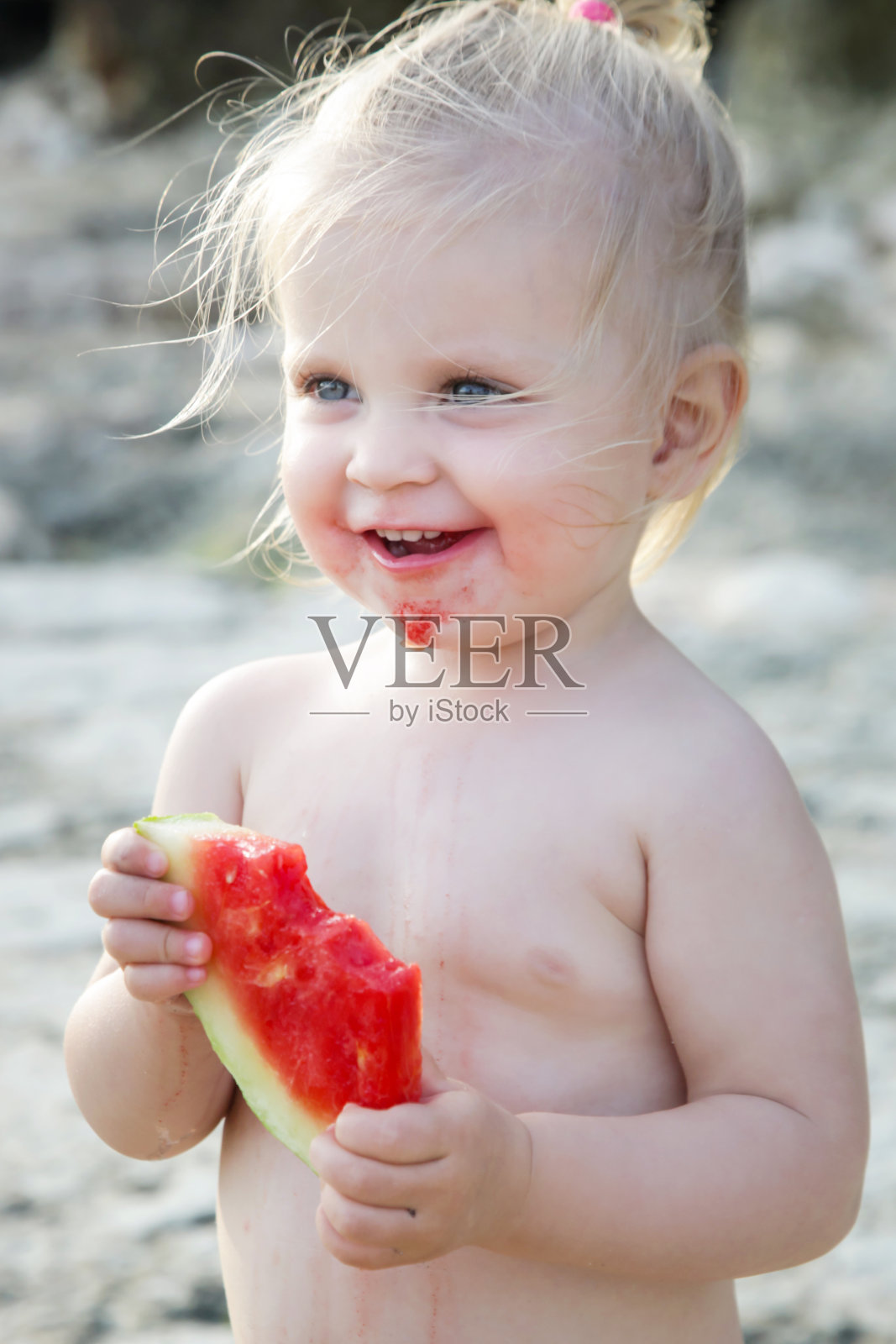 快乐的金发女孩吃着一片西瓜，偷拍着户外写真照片摄影图片