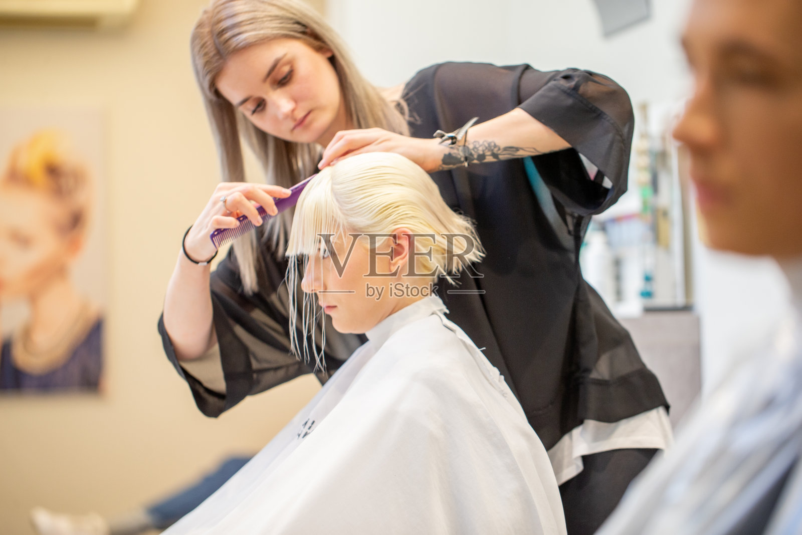 年轻女性美发师剪一个年轻的成年妇女的头发照片摄影图片