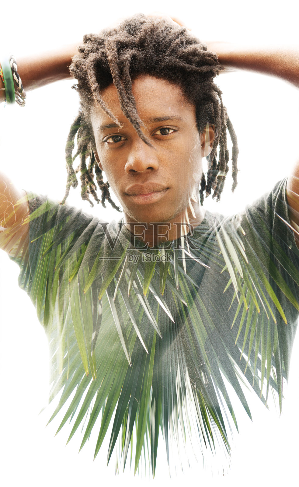 一张深色皮肤、梳着脏辫、双手放在脑后的男子的双重曝光照片，加上一张郁郁葱葱的绿色热带植物的照片照片摄影图片
