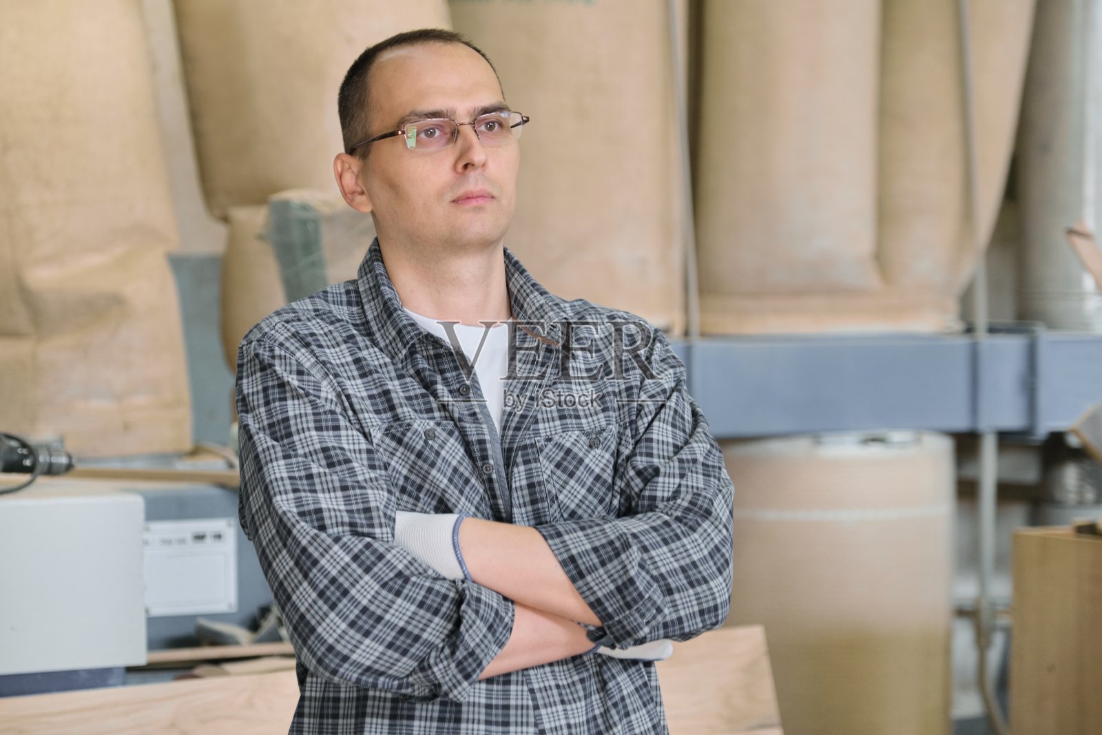 工业生产中男性工人的肖像。自信的男人双手合十。照片摄影图片