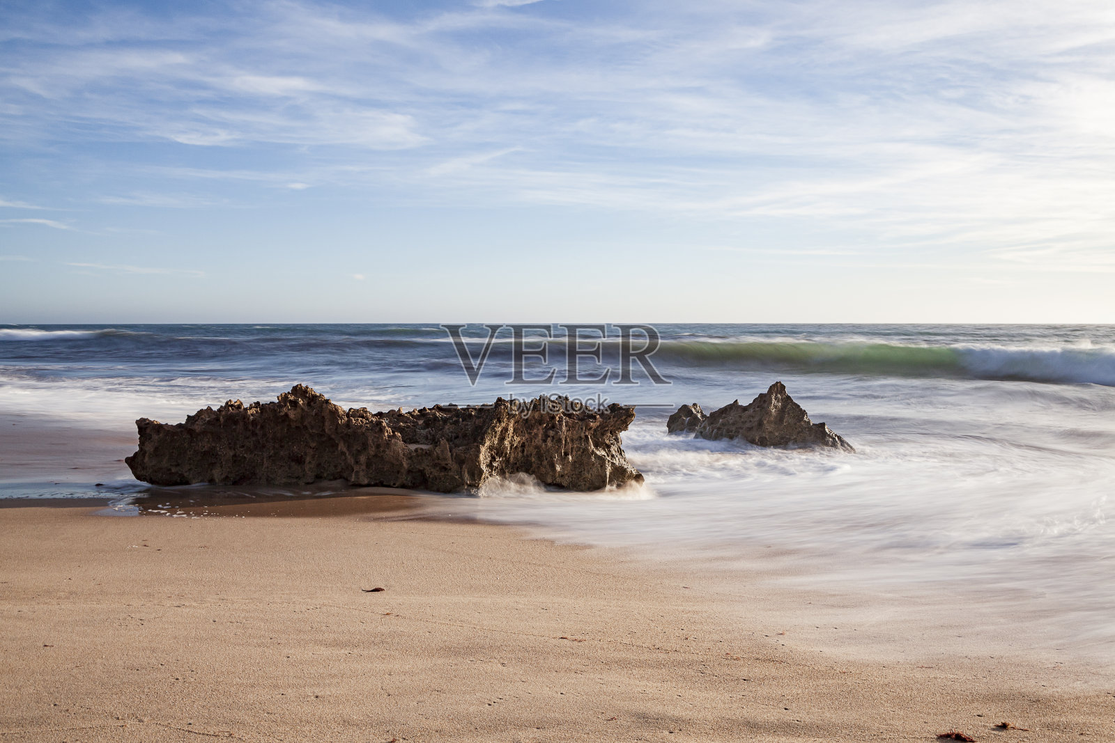 岩石拍打着海滩上的浪花。照片摄影图片
