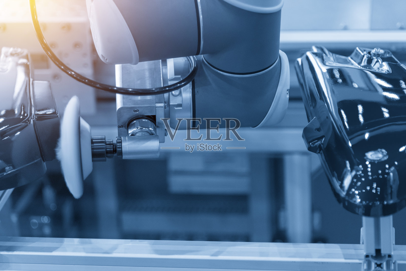 在浅蓝色场景中，汽车工厂的抛光机器人。照片摄影图片