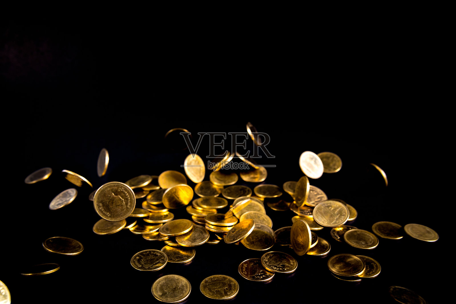 金币落在黑暗的背景下，经营理念。照片摄影图片