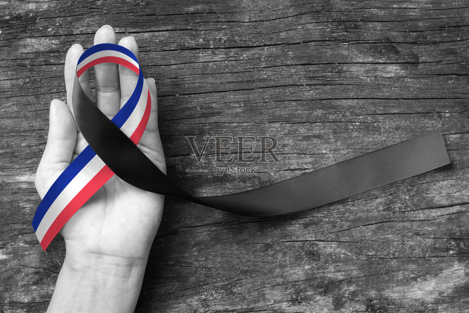 红白蓝法国国旗图案，老年背景上人手支撑黑色缎带(剪报路径)。照片摄影图片