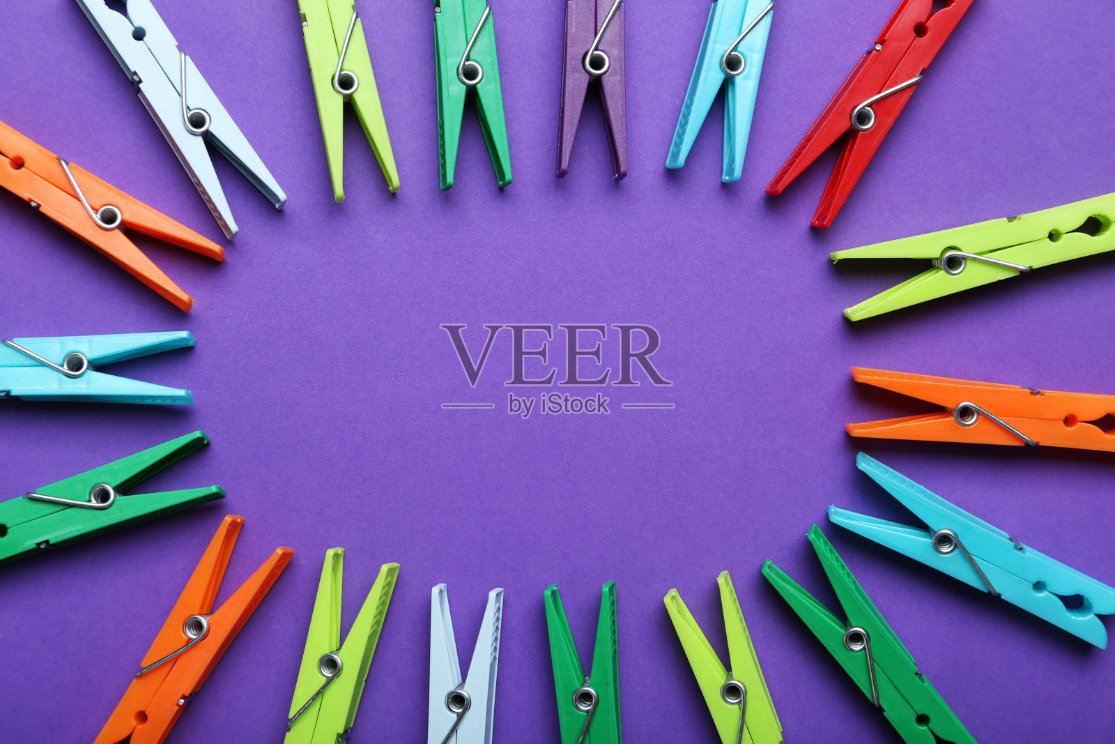 紫色背景上的塑料衣夹照片摄影图片