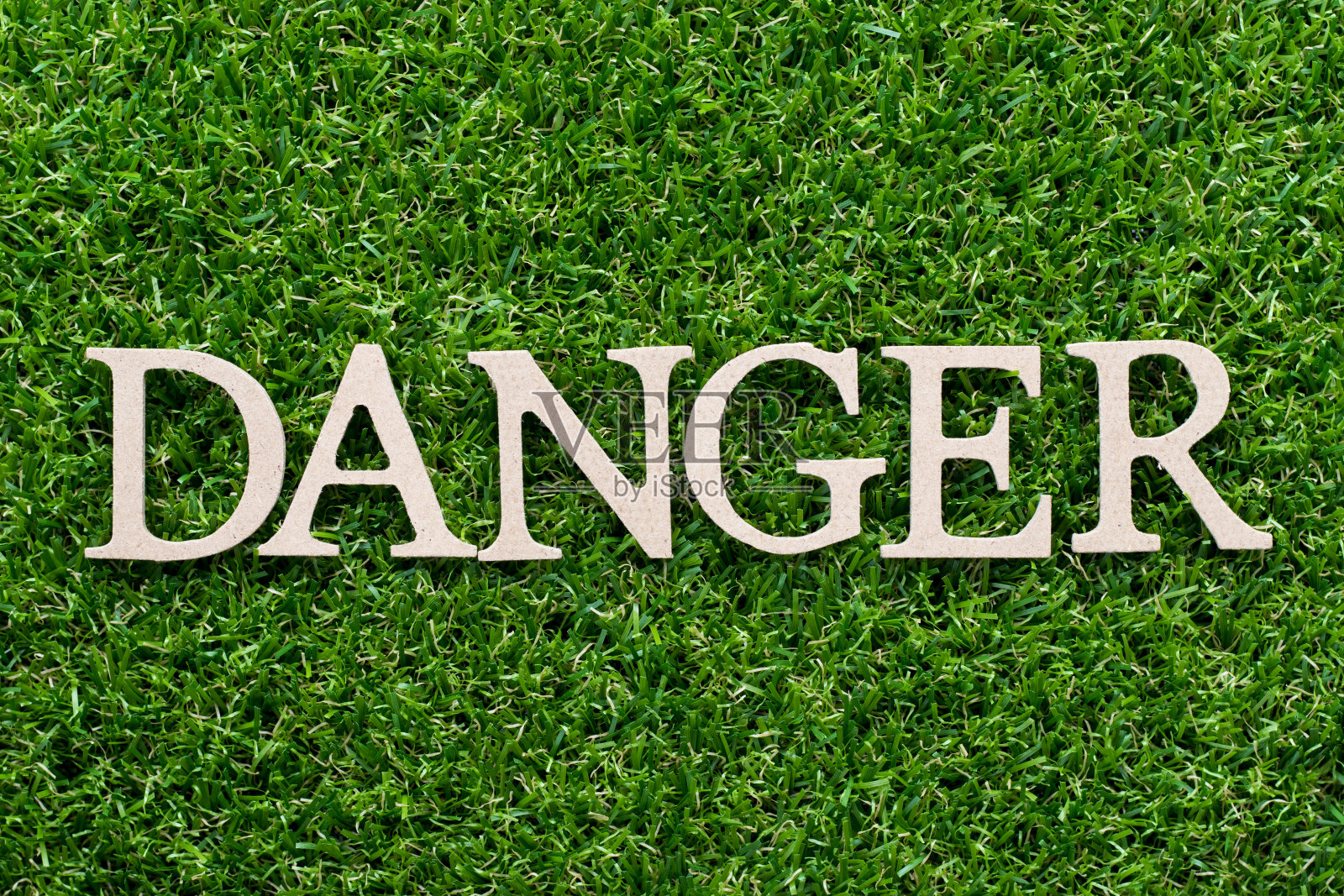 木字母在字危险上人工绿草背景照片摄影图片