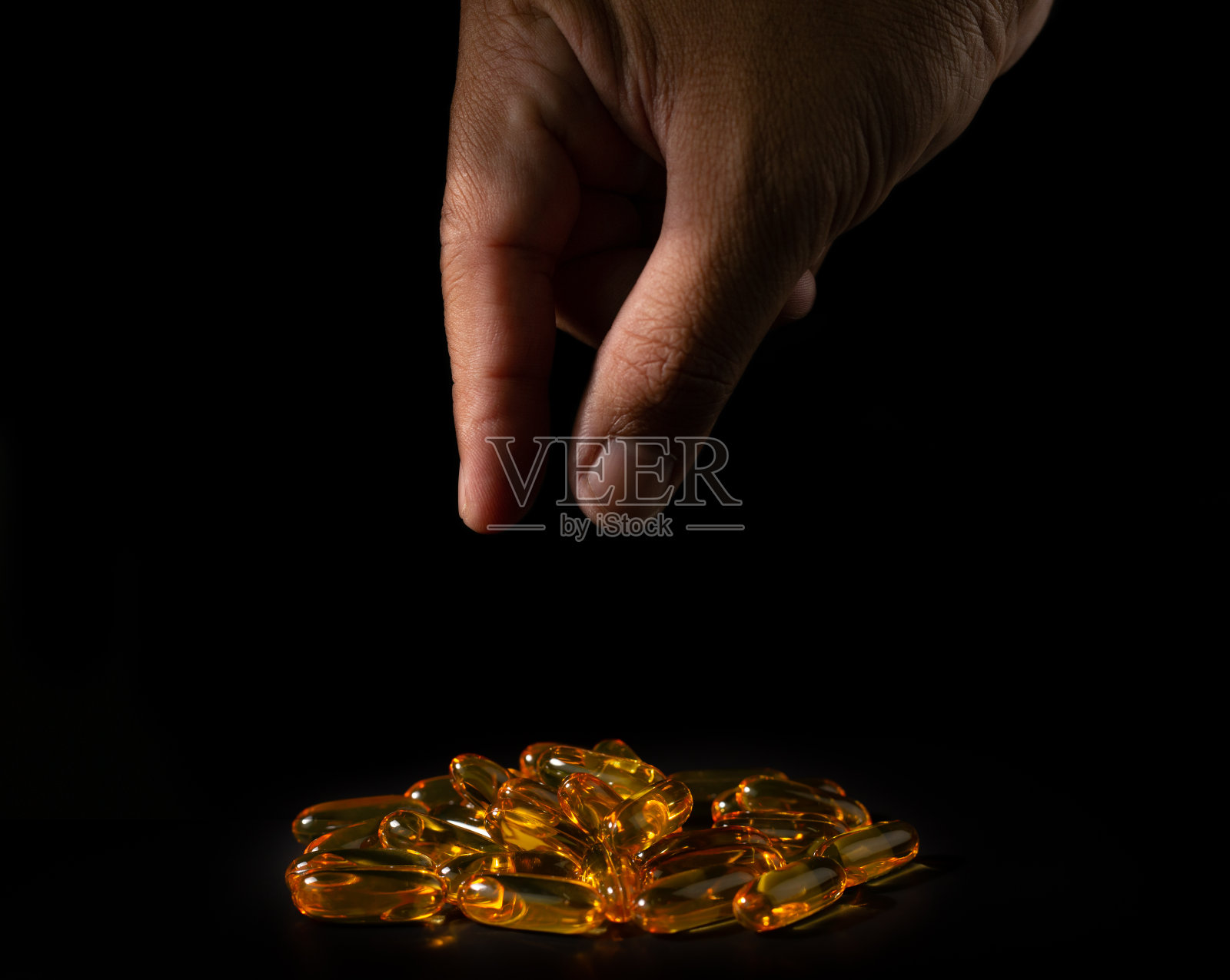 鱼油胶囊和手指照片摄影图片