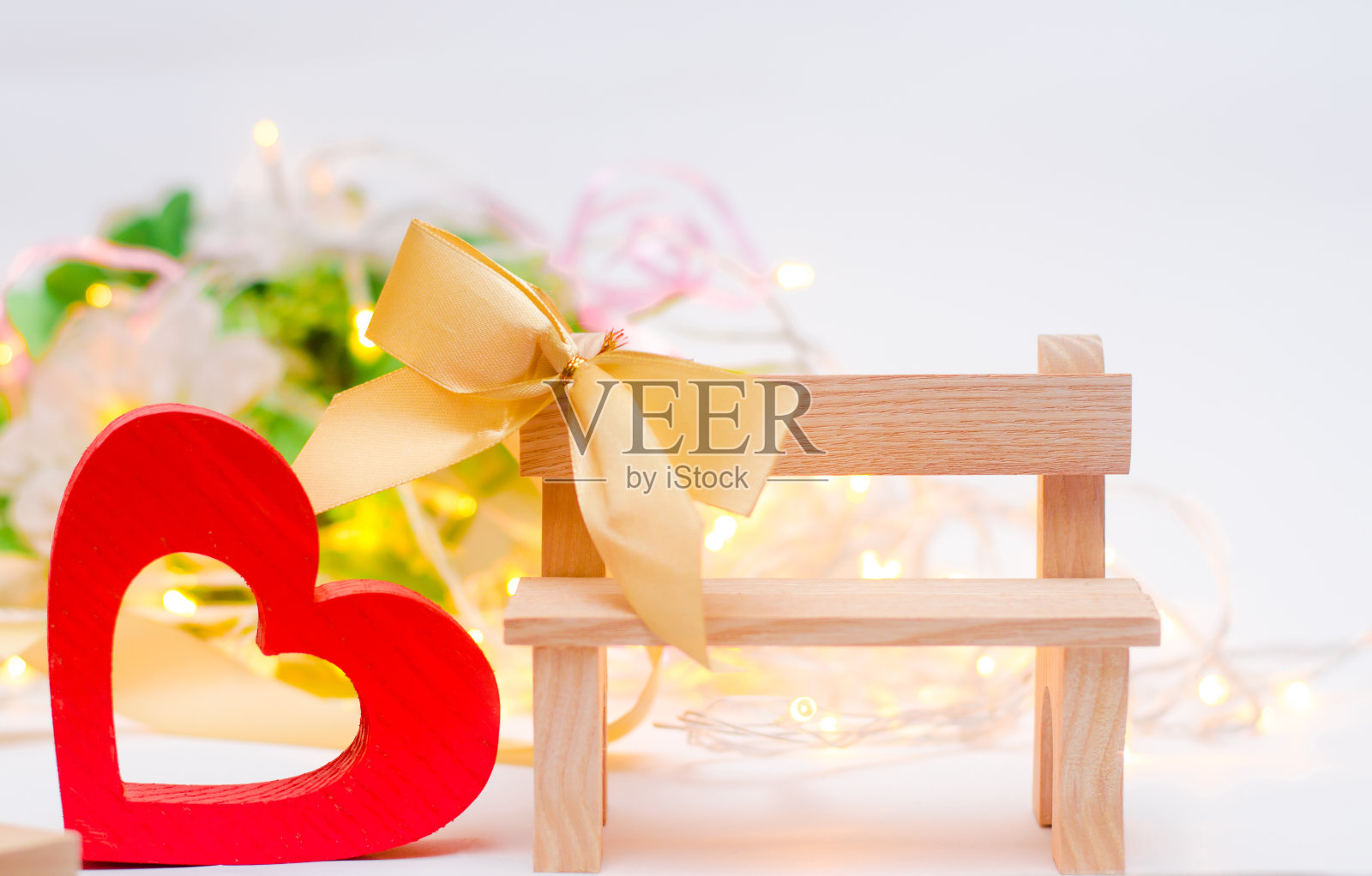 白色背景的长凳上放着带弓的木心。情人节照片摄影图片