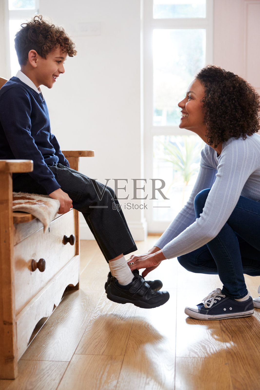 单身母亲在家给儿子穿校服准备上学的第一天照片摄影图片