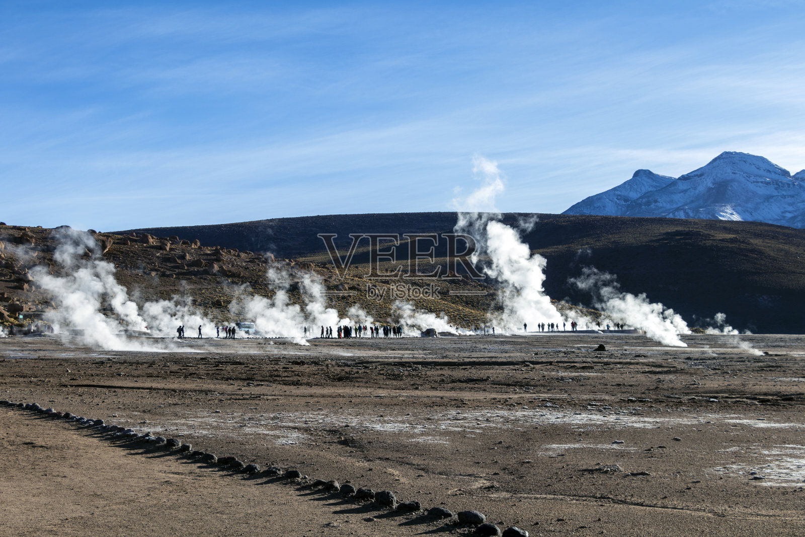 智利，阿塔卡马沙漠:清晨日出时，埃尔塔提奥间歇泉的蒸汽热间歇泉喷发，明亮的旭日从后面升起照片摄影图片