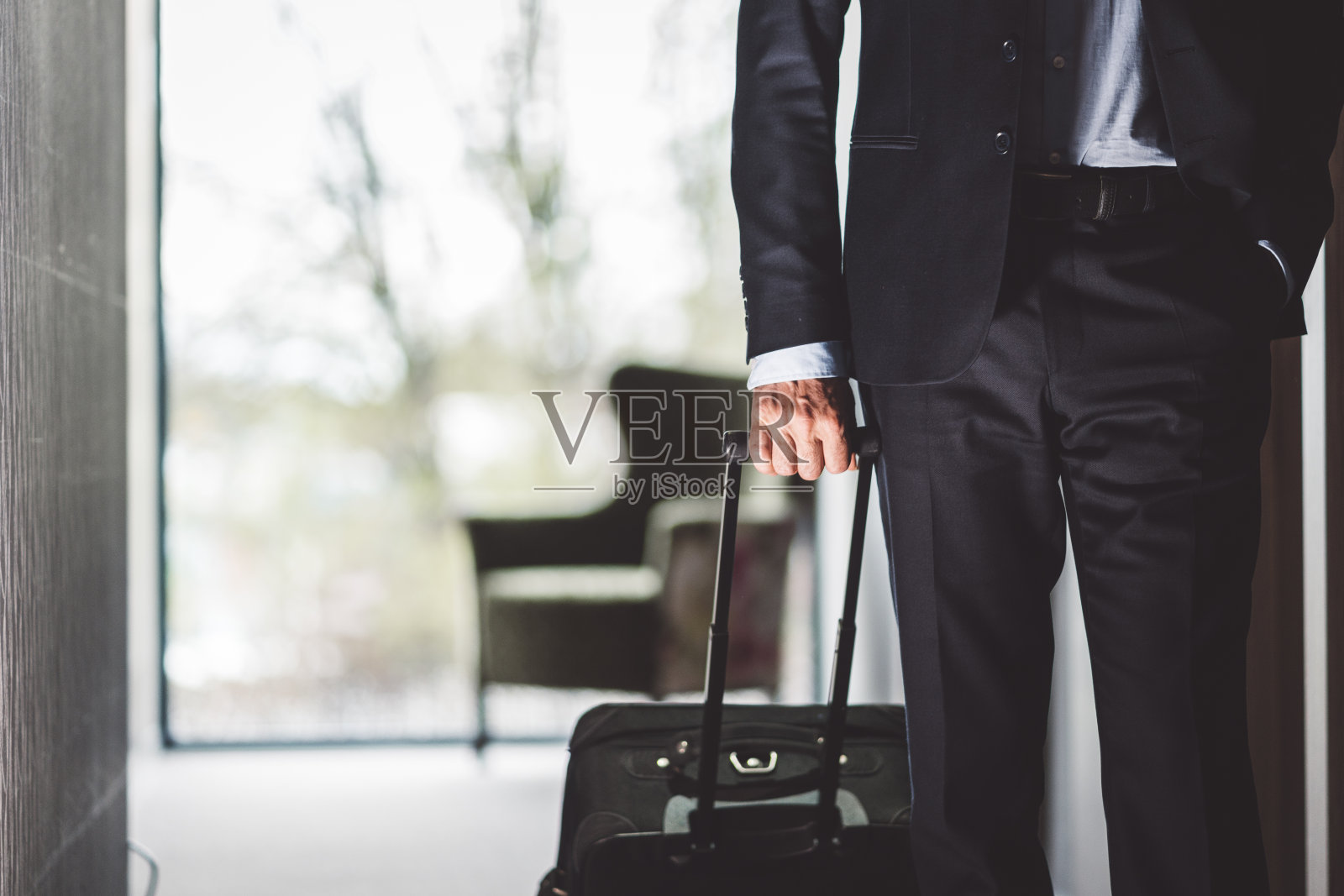 一个穿着西装拿着行李箱的男人走进酒店照片摄影图片