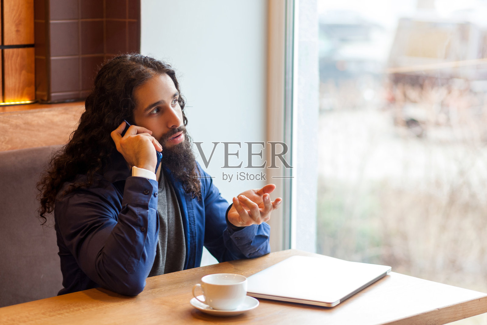年轻的自由职业者在咖啡馆使用笔记本电脑讲电话照片摄影图片