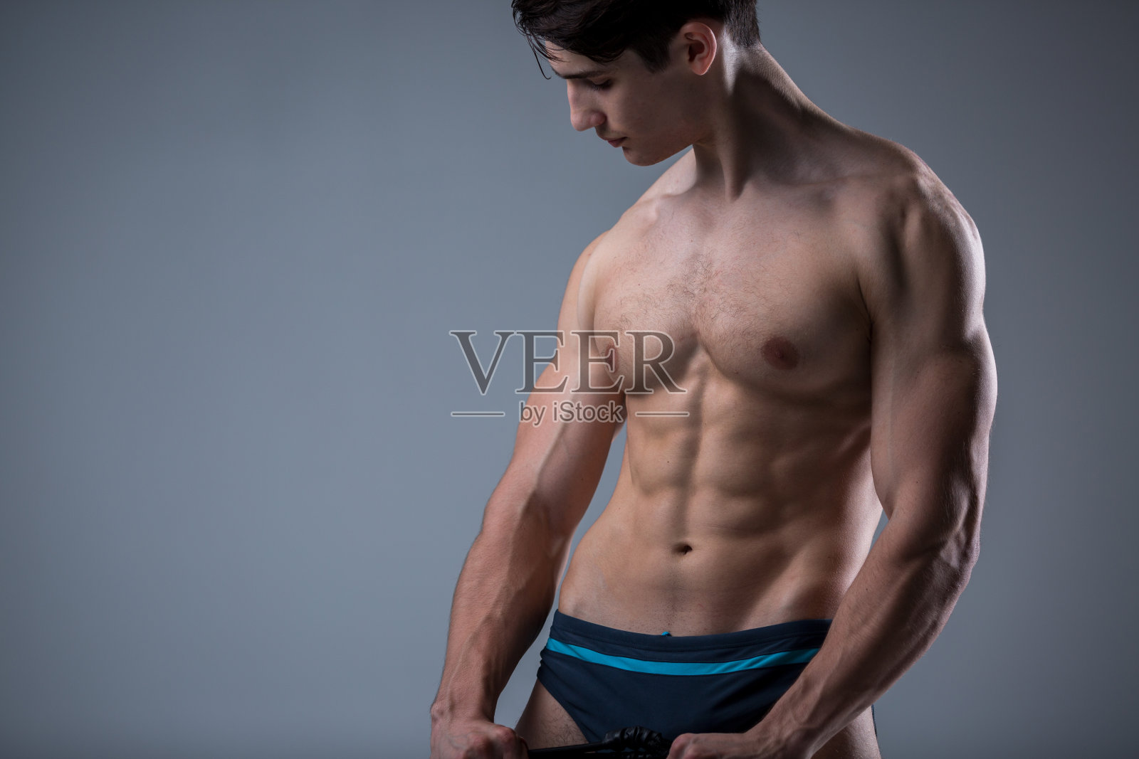 肌肉健康年轻男性古董完美肌肉六块腹肌和裸露的胸部。健美模型训练与拉伸弹性在工作室的黑暗背景。运动训练健身照片摄影图片