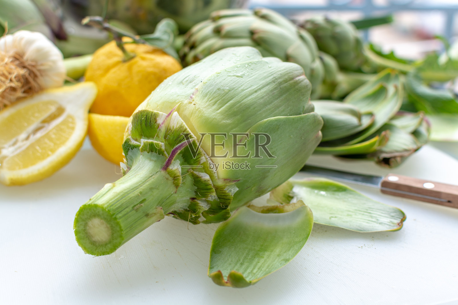 从希腊阿格里达的朝鲜蓟种植园准备新鲜的生朝鲜蓟，准备用柠檬烹饪照片摄影图片