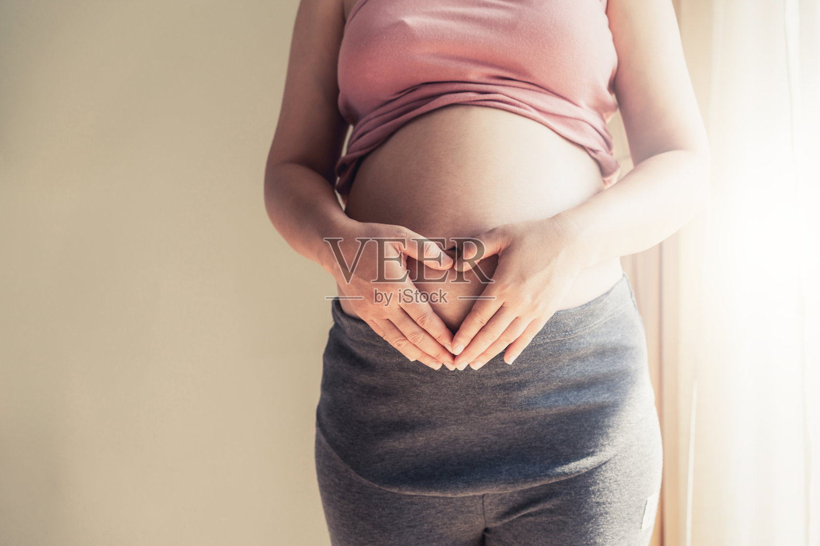 孕妇在家照顾孩子时感到快乐。年轻的孕妇抱着怀孕的肚子里的婴儿。孕产妇产前护理与妇女怀孕的概念。照片摄影图片