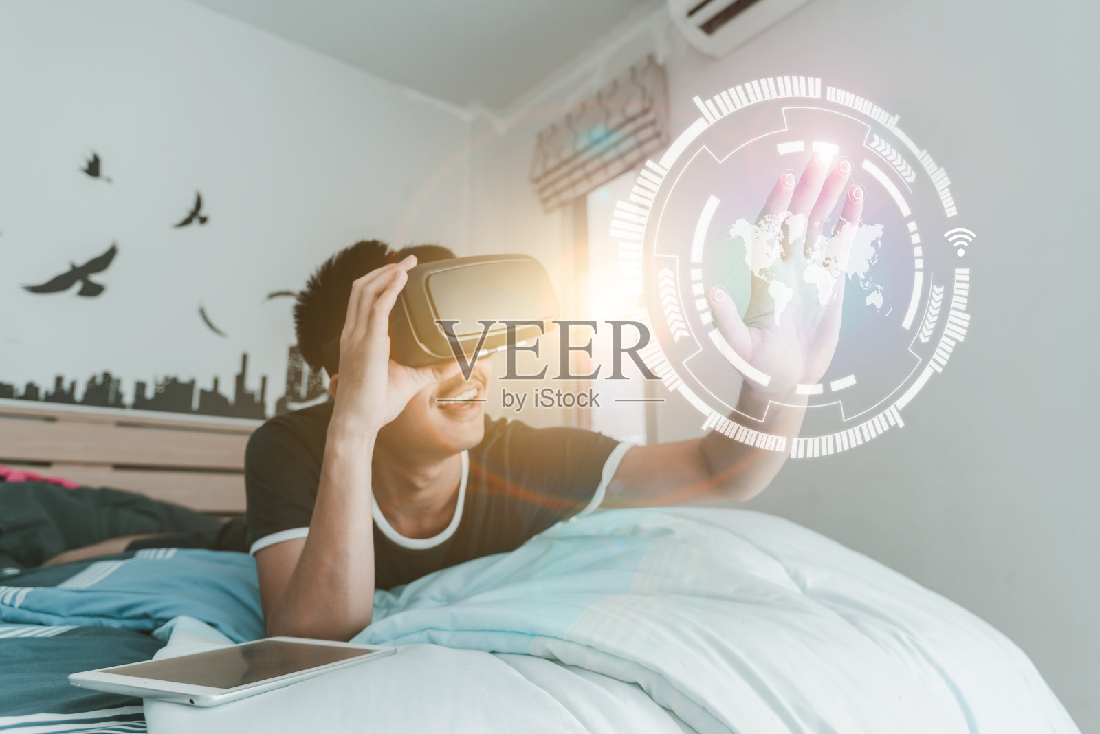 年轻人在卧室里戴着虚拟现实眼镜，智能手机在卧室里使用VR头盔，数字屏幕的概念，连接和接口照片摄影图片