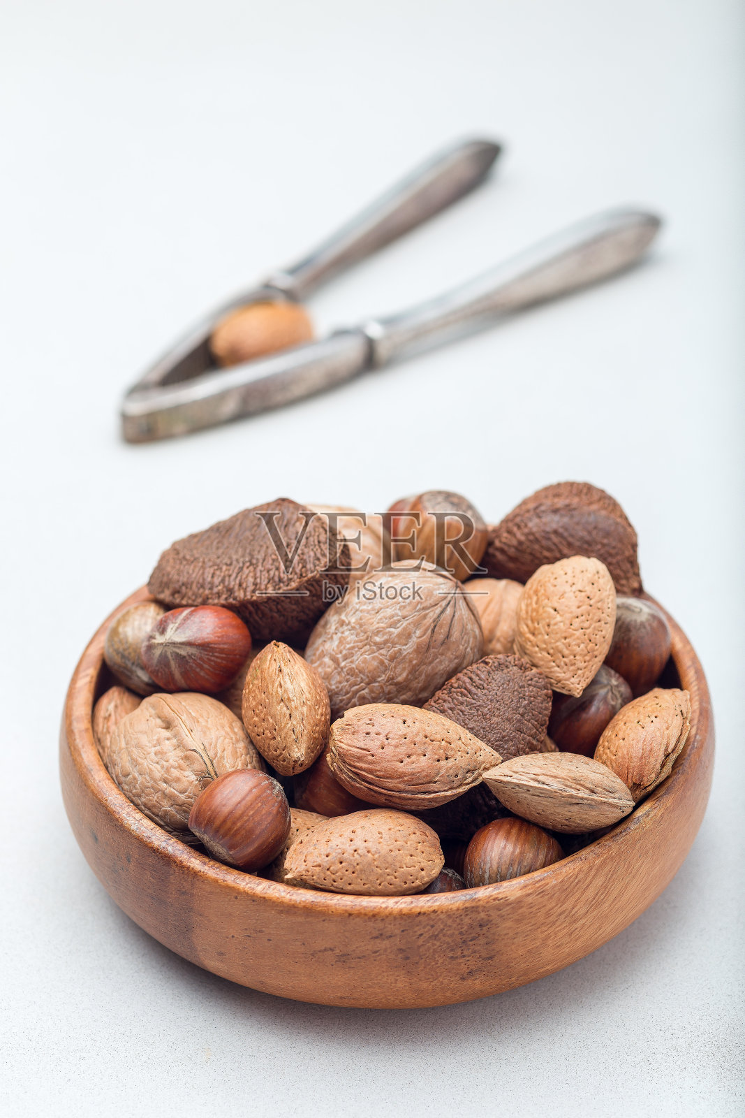 不同种类的坚果在壳，榛子，核桃，杏仁和巴西坚果在木碗的背景上，垂直照片摄影图片