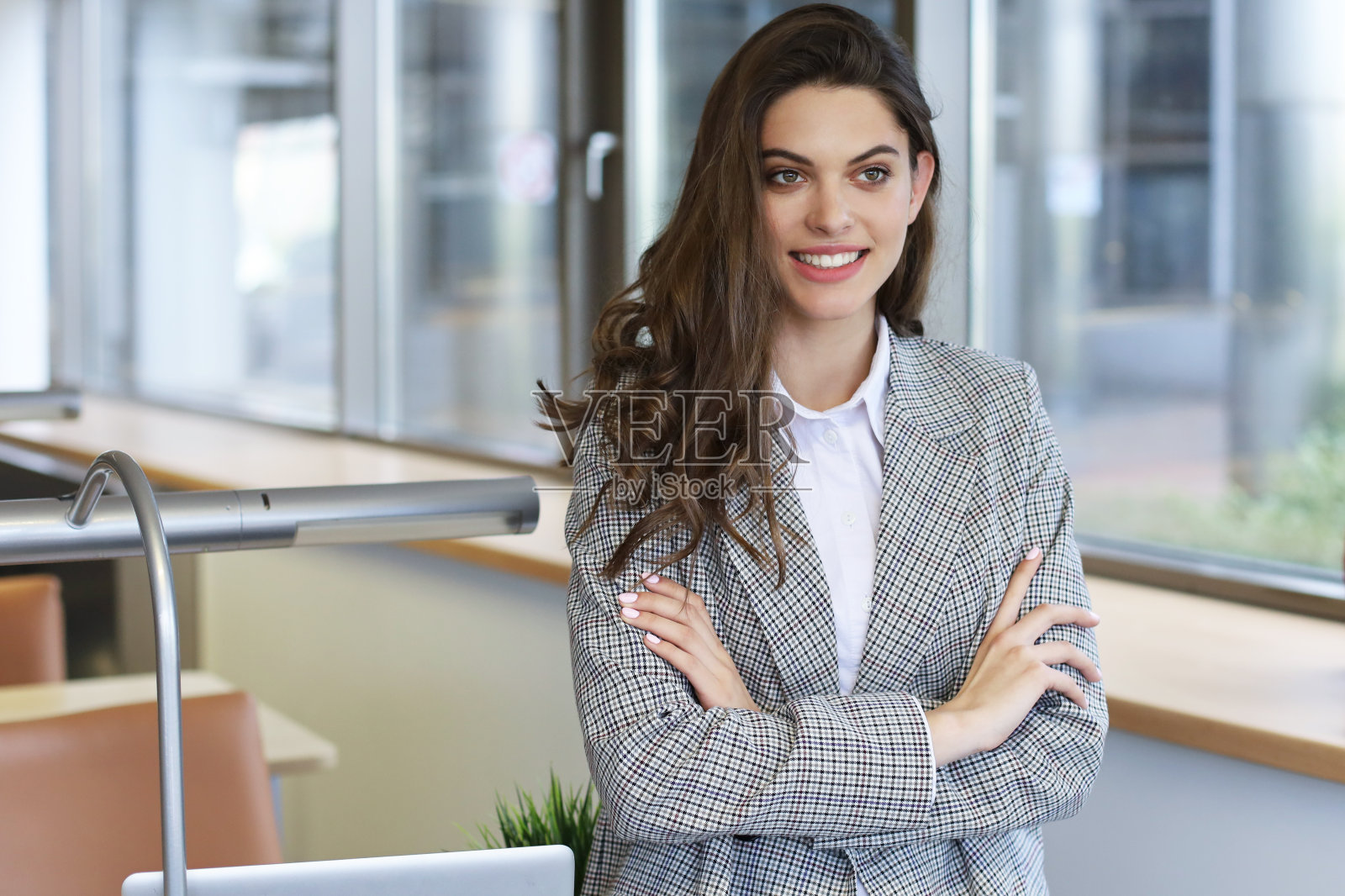 漂亮的女商人站在办公室的桌子旁边。照片摄影图片