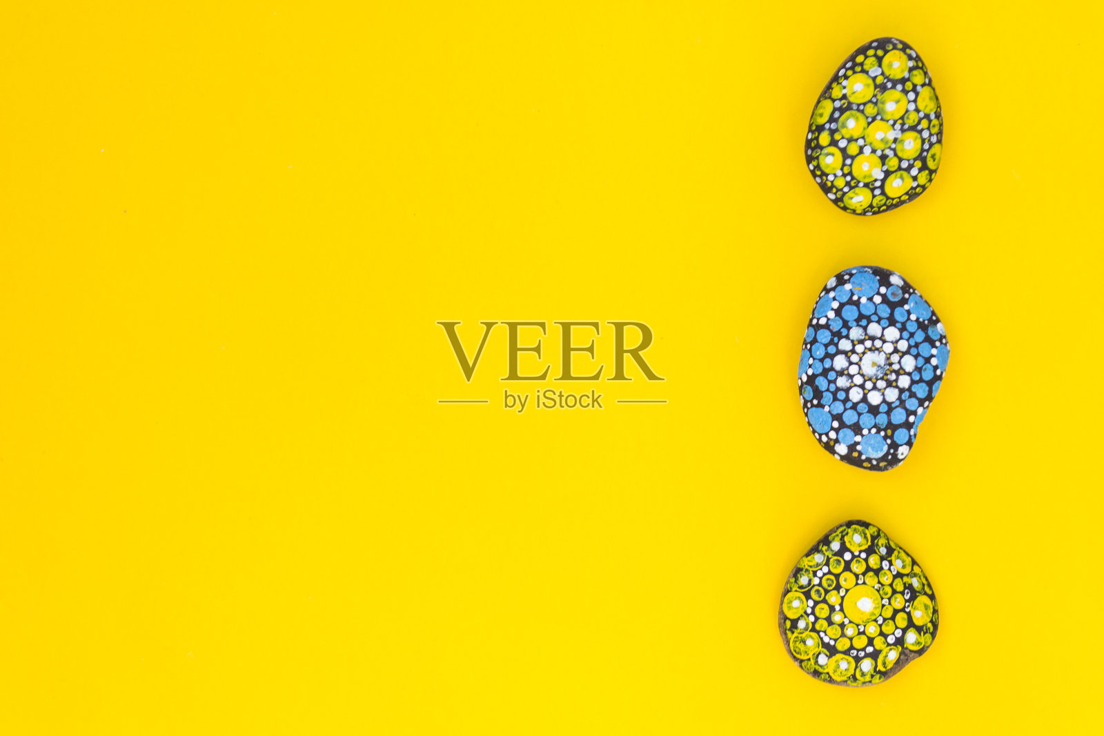 黄色的背景上，画着彩色的石头。这里有文本的位置。照片摄影图片