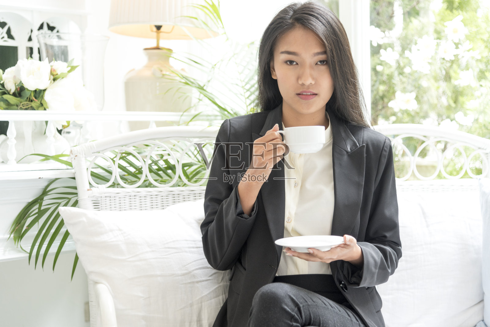 工作漂亮的女人坐在黑白沙发上用科技与智能平板电脑现代生活方式。搜索互联网和网上购物。企业女性的概念照片摄影图片