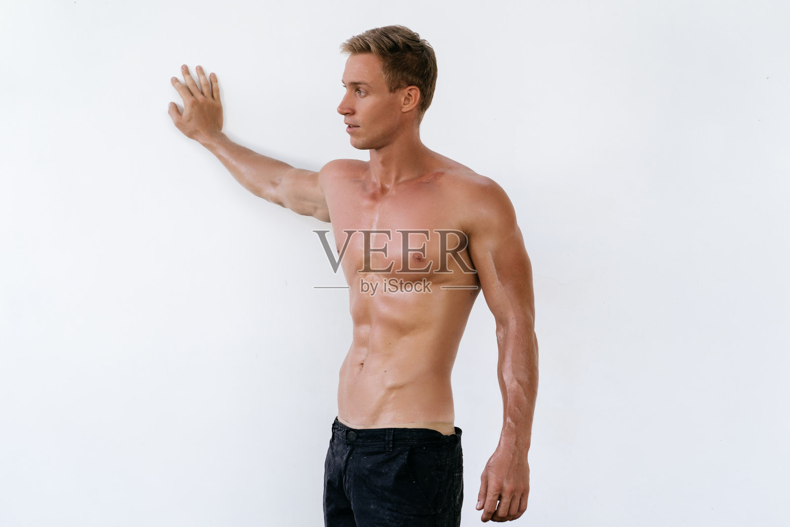 运动员的肖像与赤裸的躯干在白色墙壁的背景照片摄影图片