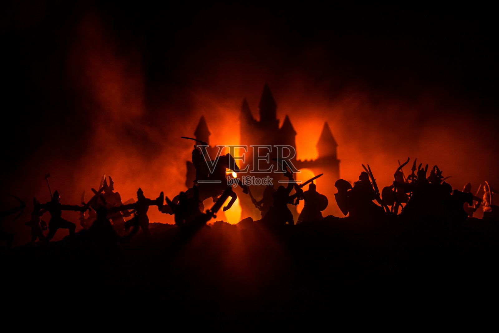 有骑兵和步兵的中世纪战斗场景。人物的剪影作为单独的对象，战士之间的战斗在黑暗色调的雾背景与中世纪城堡。照片摄影图片