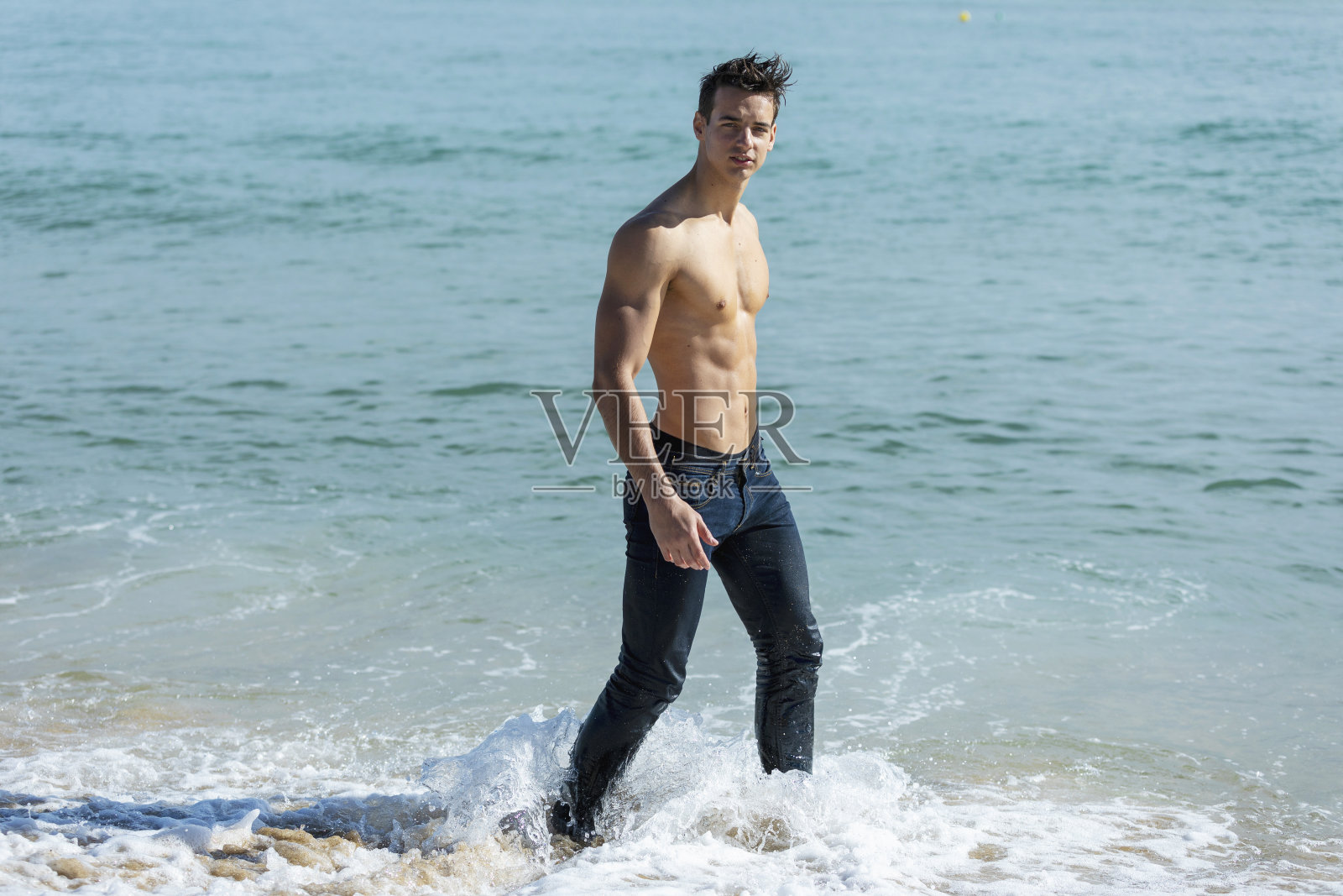 在一个阳光明媚的日子里，一个英俊的肌肉男在海边照片摄影图片