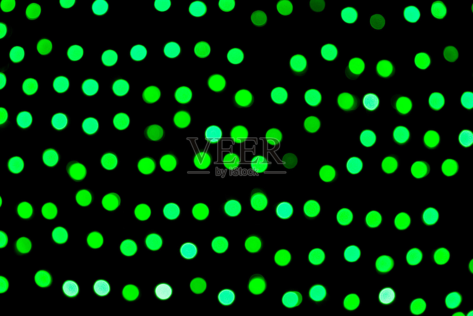 在黑色背景上不聚焦的抽象绿色散景。散焦和模糊了许多圆光照片摄影图片