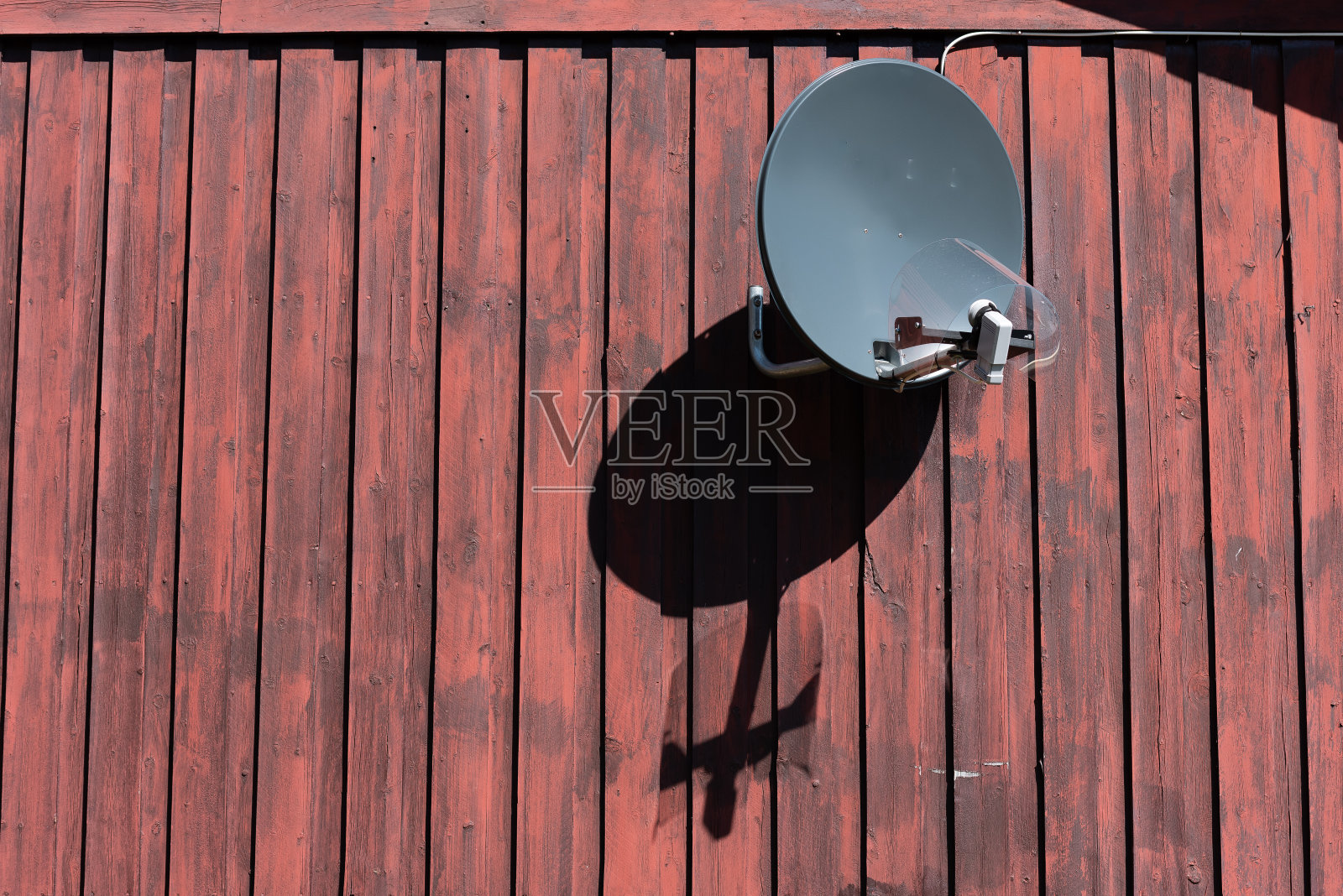 旧木墙上的抛物面天线。照片摄影图片