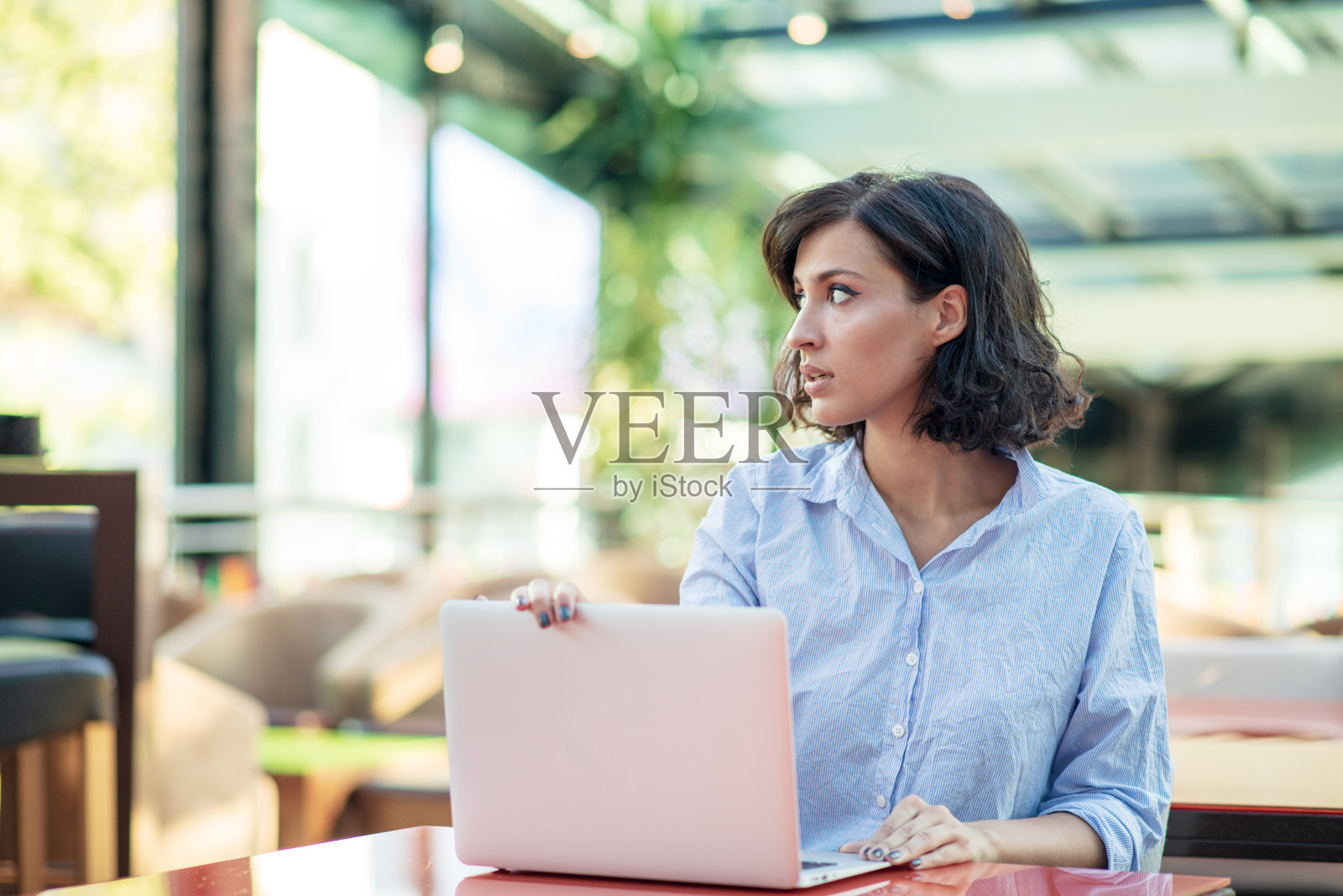 年轻漂亮的女孩拿着笔记本电脑坐在咖啡馆里照片摄影图片