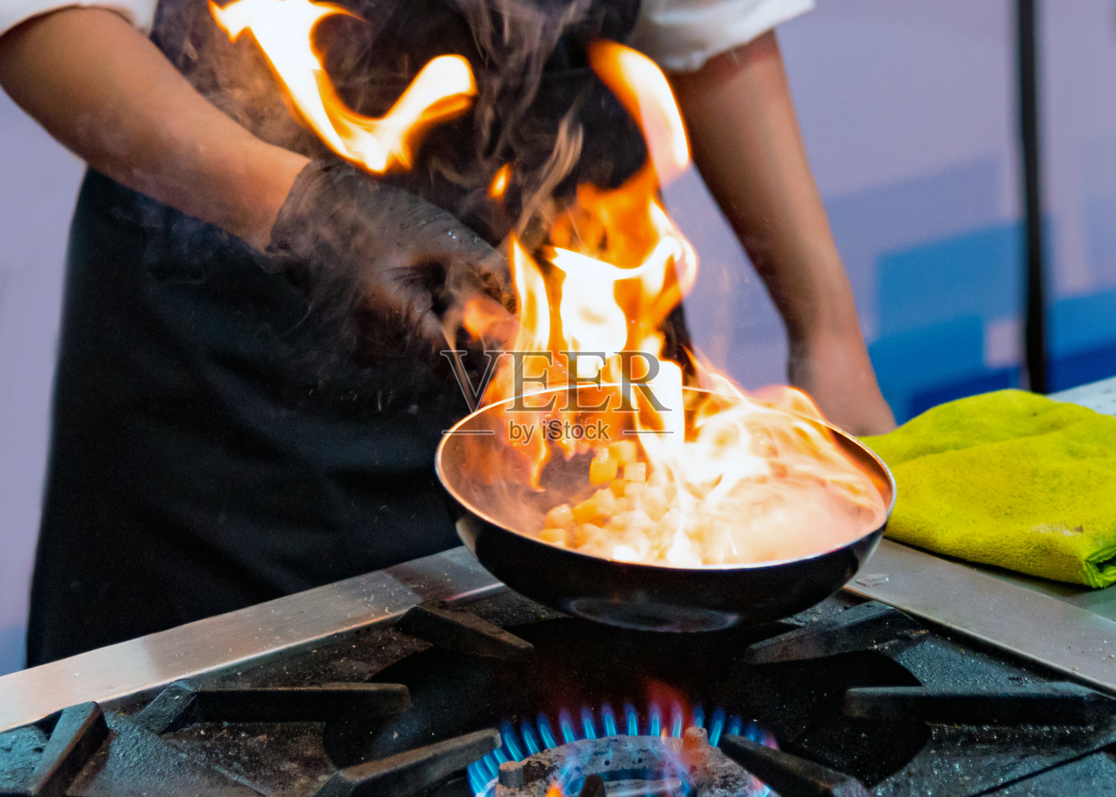 厨师在厨房炉子上用煎锅用火焰烹饪照片摄影图片