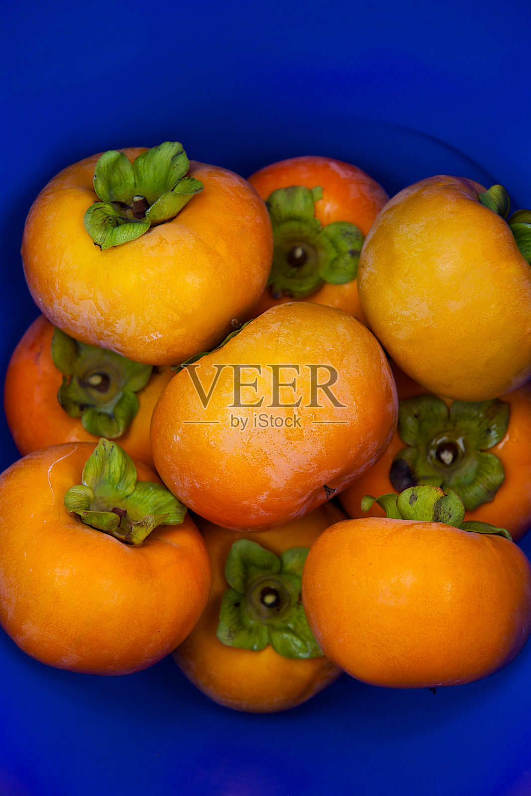 桶里的柿子。照片摄影图片