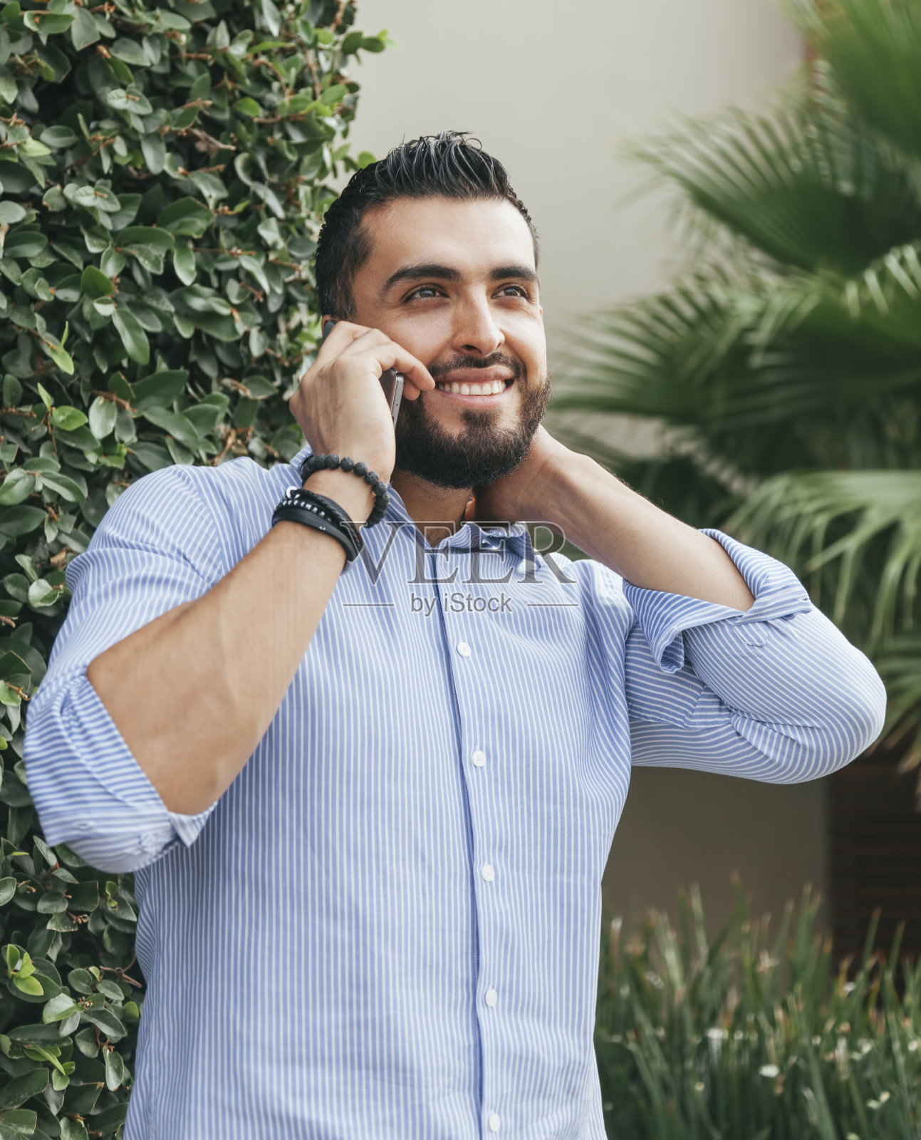 年轻的拉丁美洲人微笑着在户外用手机说话照片摄影图片