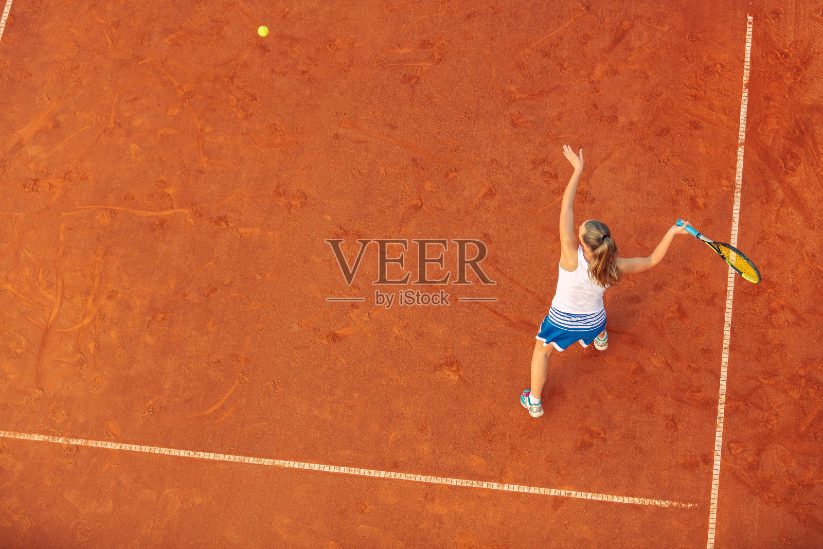 空中拍摄的一个女子网球运动员在一个球场上的比赛。年轻女子在打网球。高角度的观点。照片摄影图片