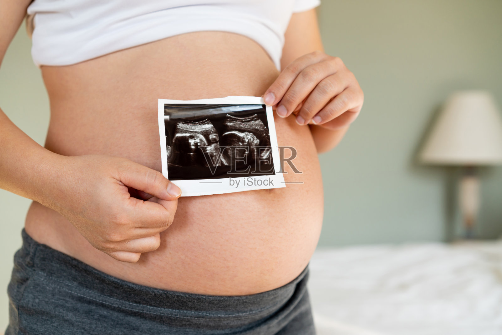 孕妇在家照顾孩子时感到快乐。年轻的孕妇抱着怀孕的肚子里的婴儿。孕产妇产前护理与妇女怀孕的概念。照片摄影图片